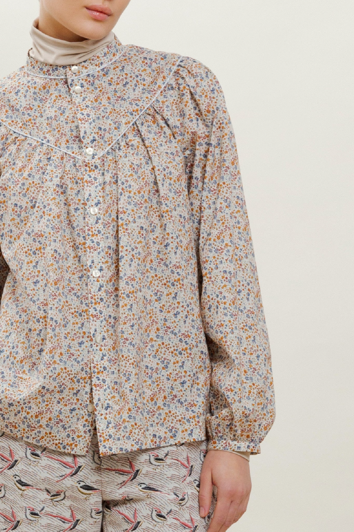 Woman in long sleeved blouse with flower pattern and trousers with pink bird pattern