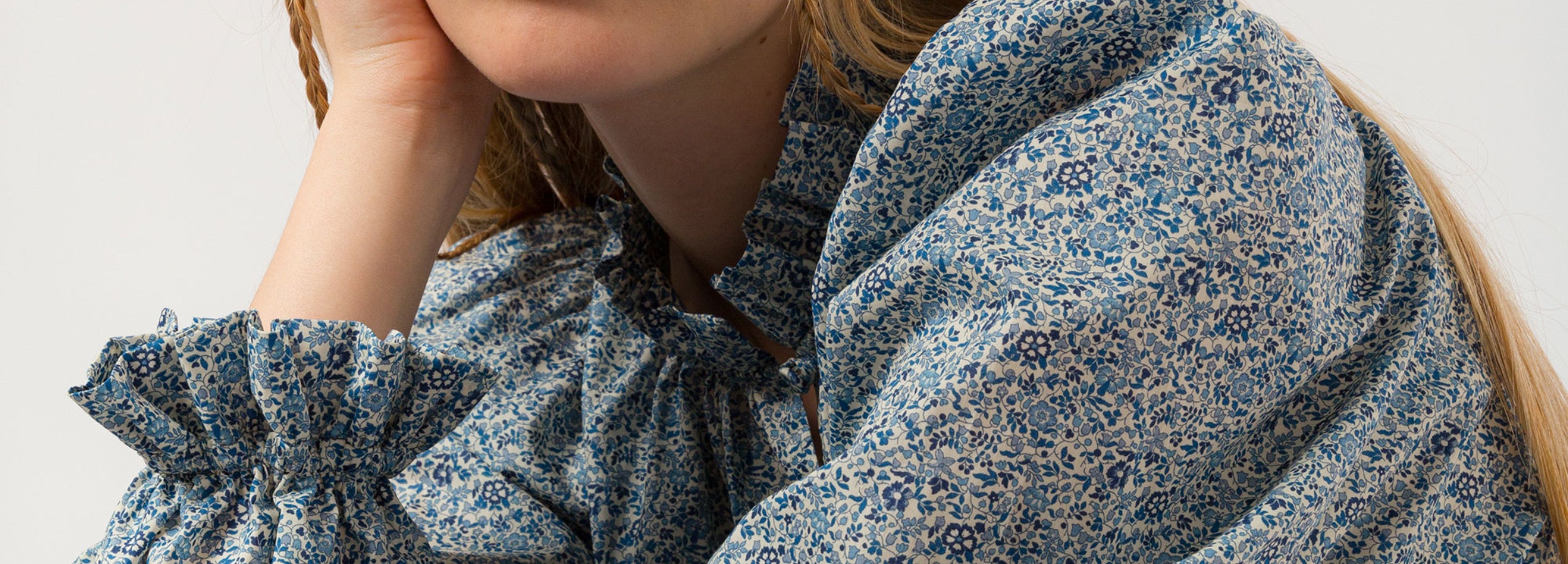 Woman in blue and white small flower patterned bluse with frilled neck and cuffs