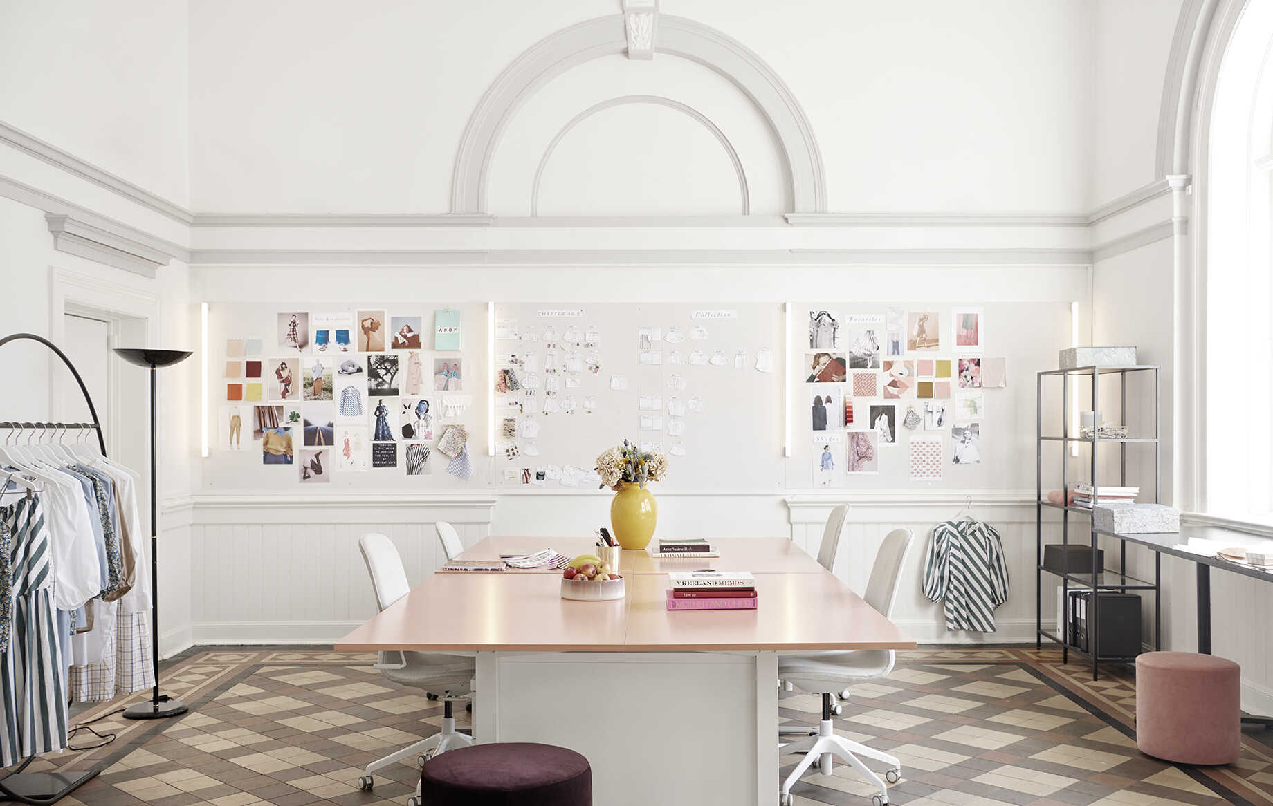 Studio with working table, 4 chairs, clothes rack and designs and notes on wall