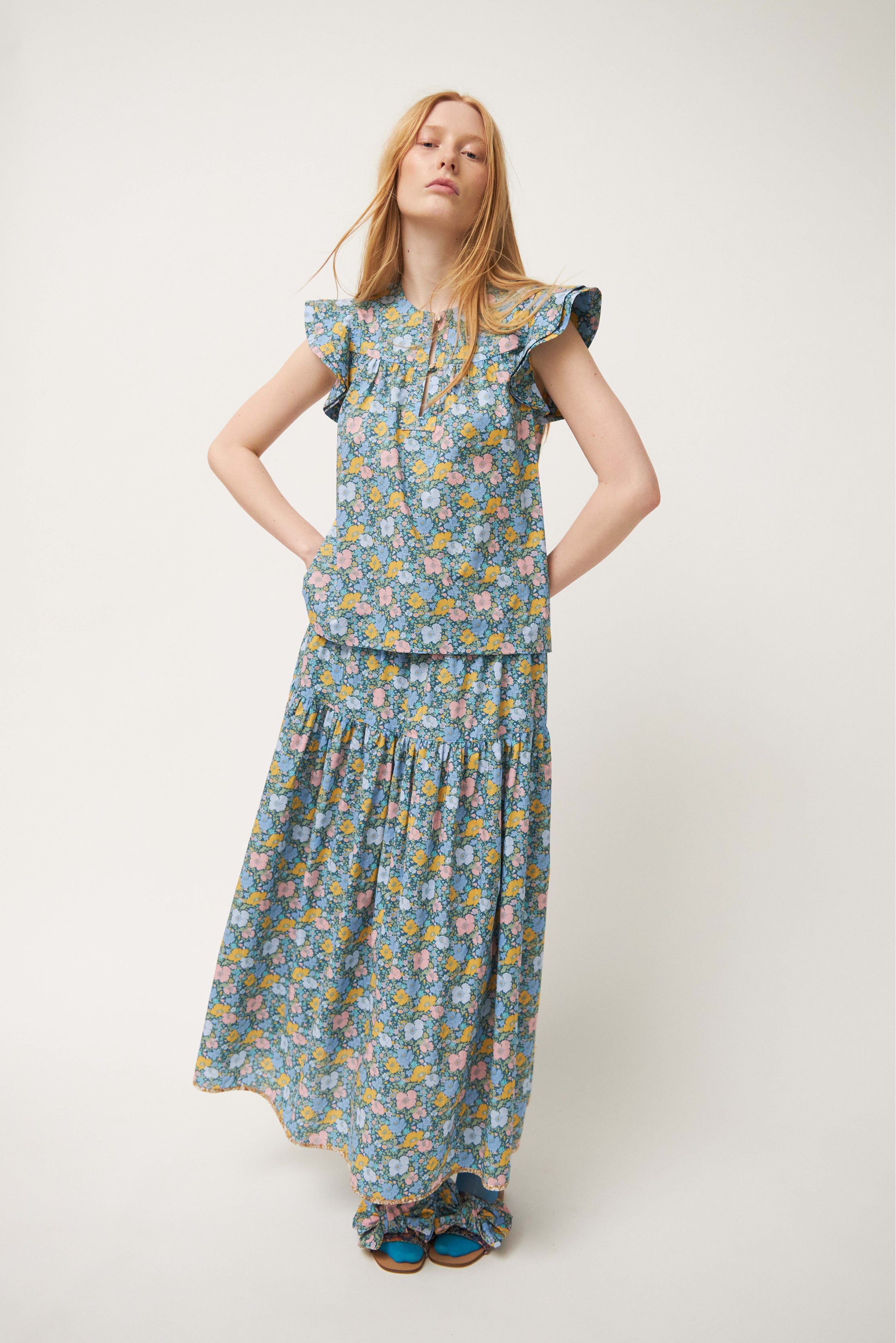 Woman in green sleeveless blouse and skirt with flower pattern and frills