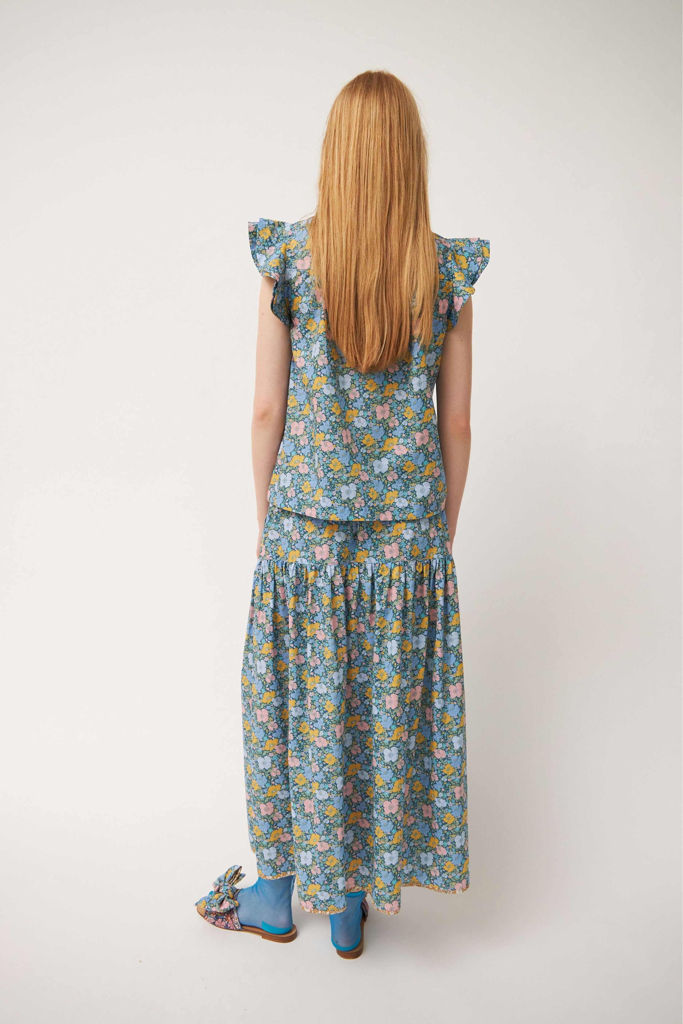Woman in green sleeveless blouse and skirt with flower pattern and frills