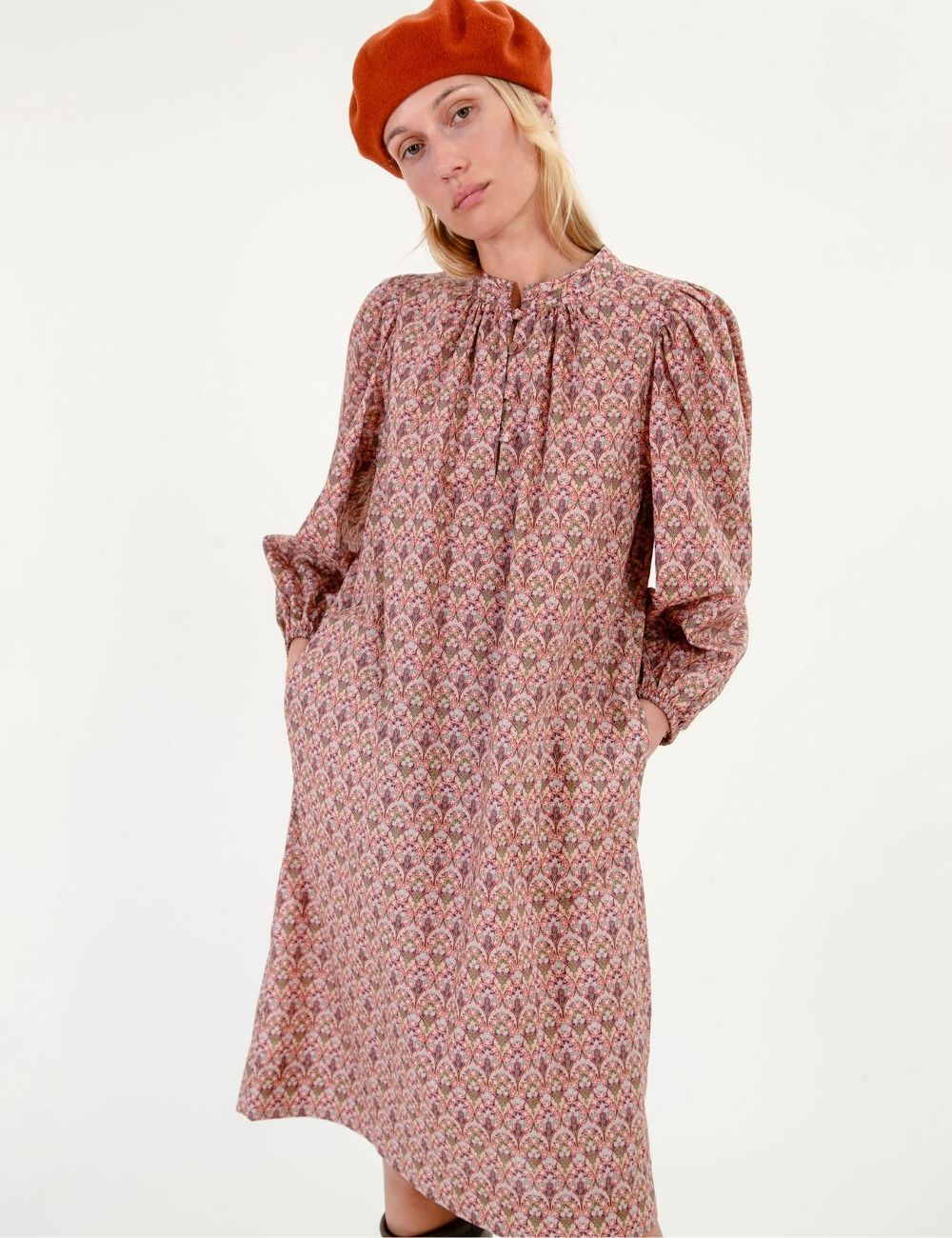 Woman wearing a short liberty cotton dress with pink floral pattern and long sleeves