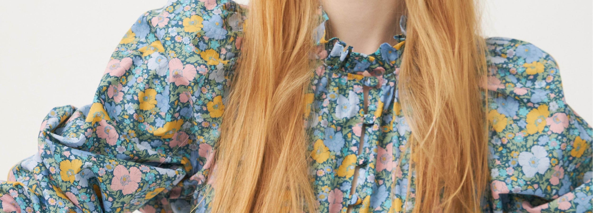 Woman in multi-colored floral patterned summer dress with puff sleeves and frilled collar