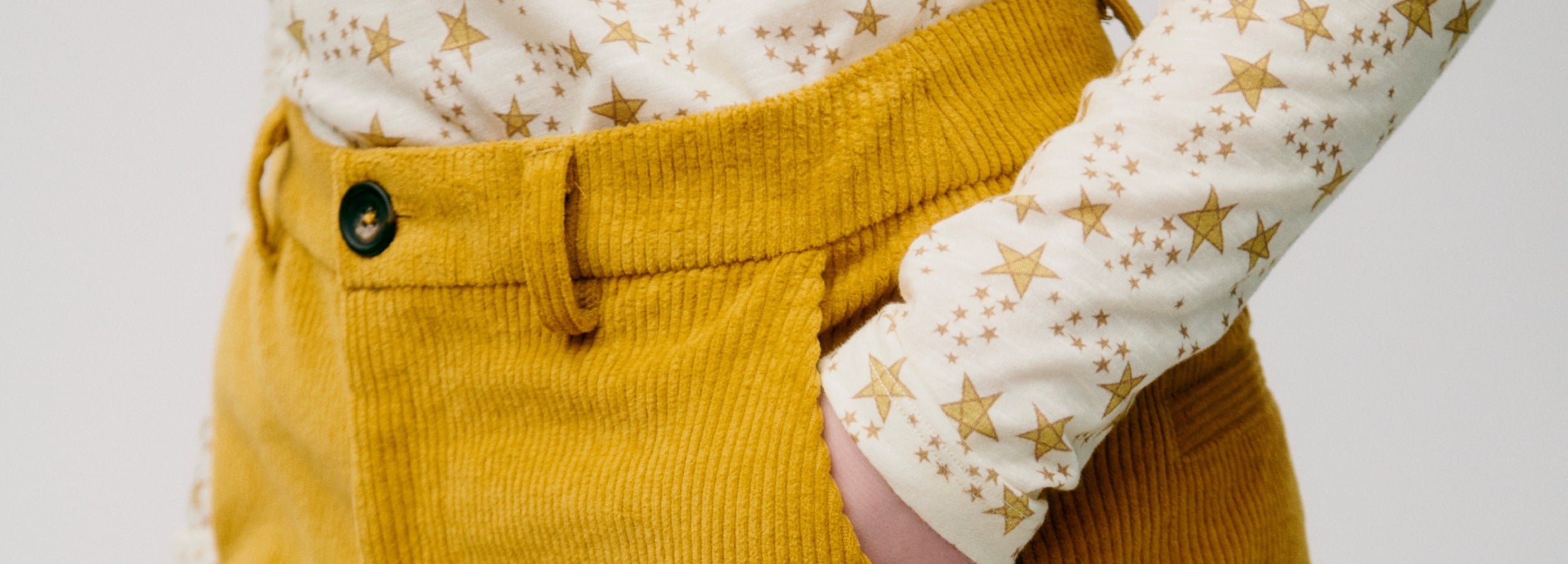 Yellow corduroy pants with a white shirt featuring star patterns on a light gray background