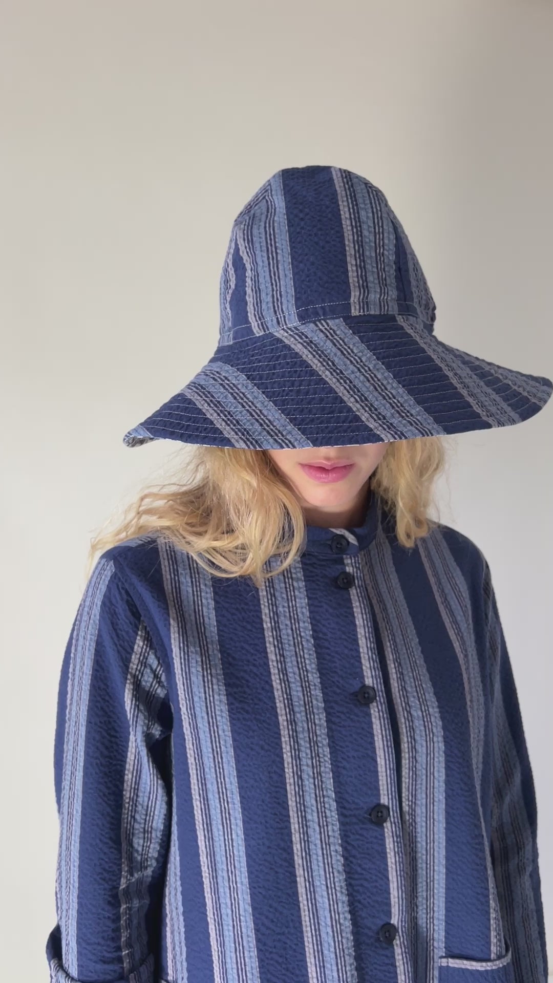 Woman in Blue and white striped hat and jacket with pockets and buttons, striped trousers and sandals with bows