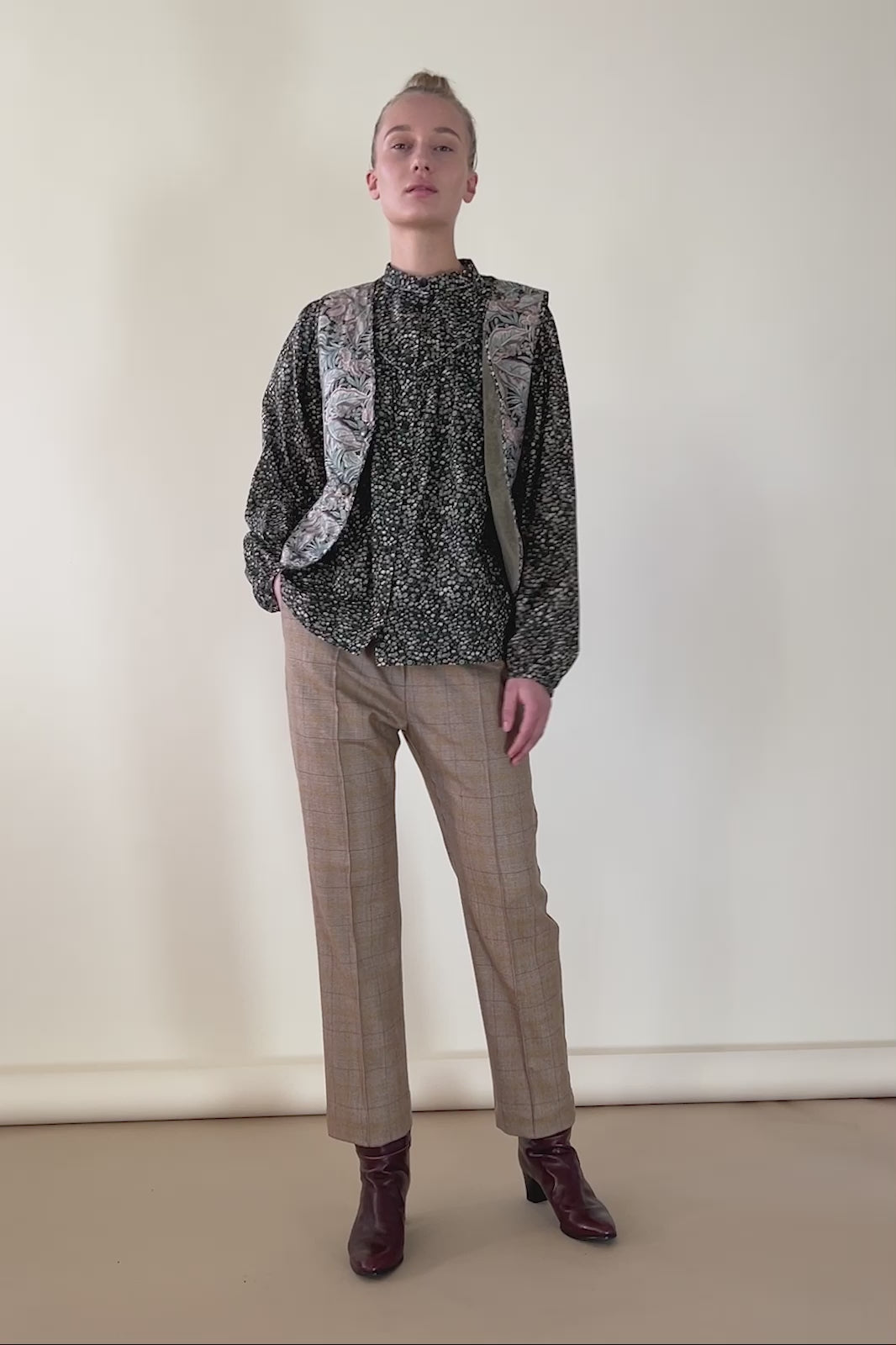 Woman in beige check print cigarette pants, shirt in Liberty cotton Marguerite floral print and vest in Liberty cotton antique paisley print in green beige and pink