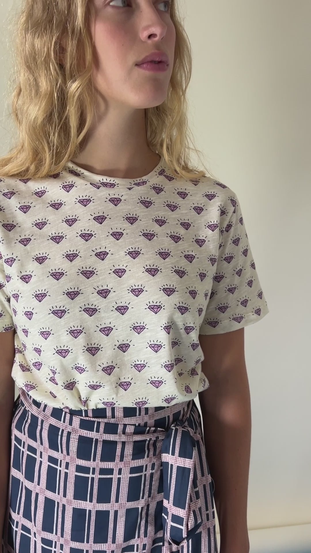 Woman in short sleeve white t-shirt with diamond pattern and checked wrap skirt