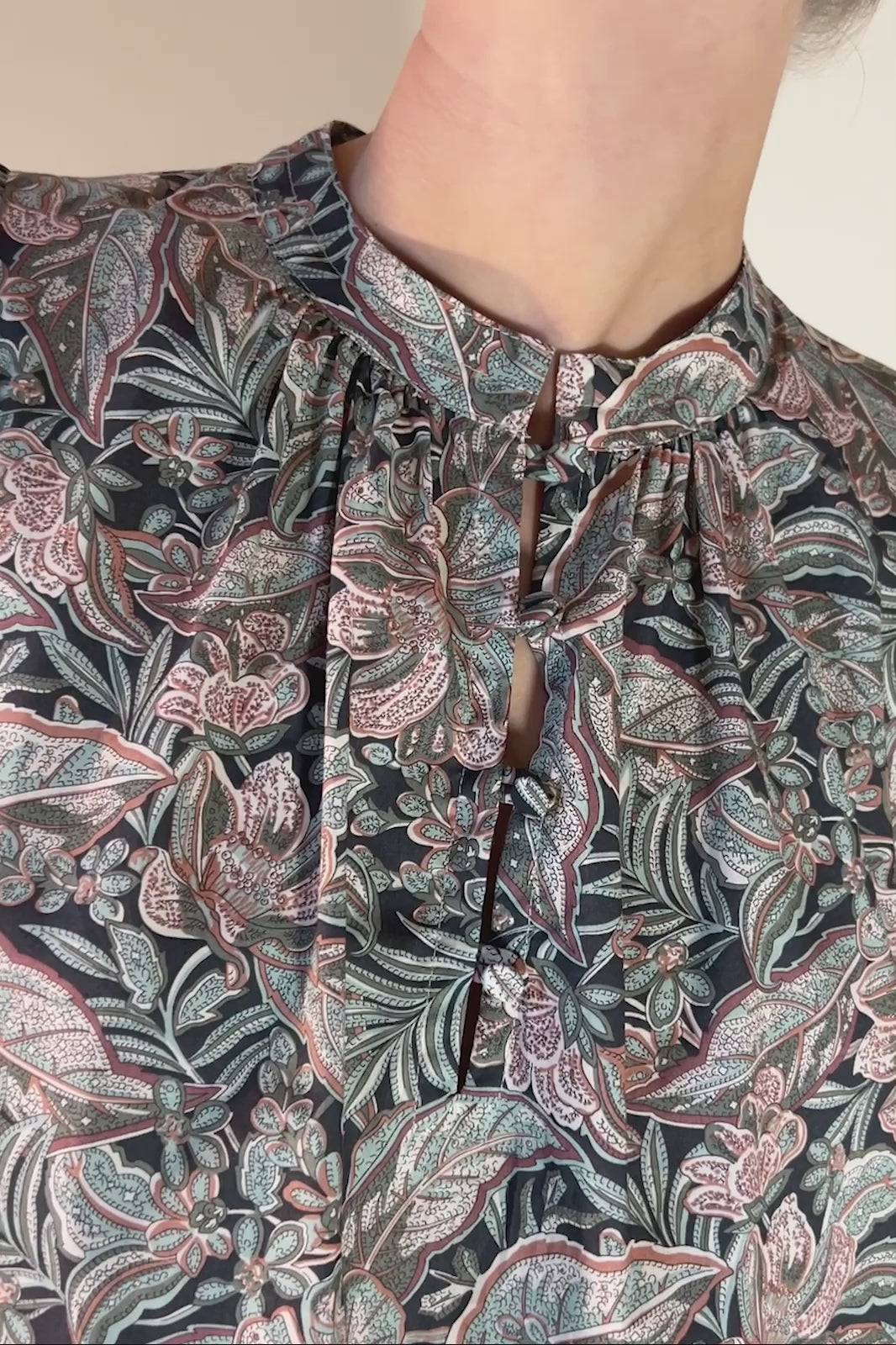 Woman in long paisley print Liberty cotton dress in green beige and pink