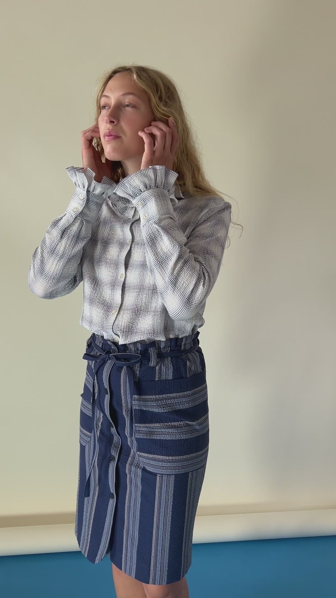 Woman in checked blouse with frills and striped skirt