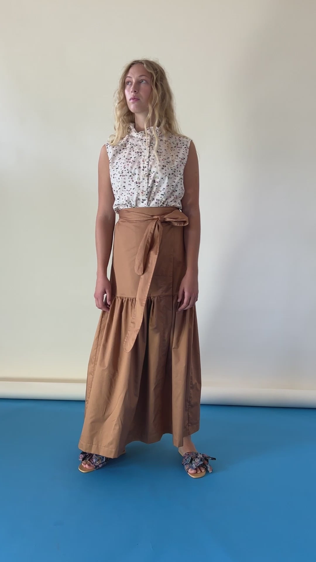 Woman in short sleeved top with flower pattern and brown wrap skirt
