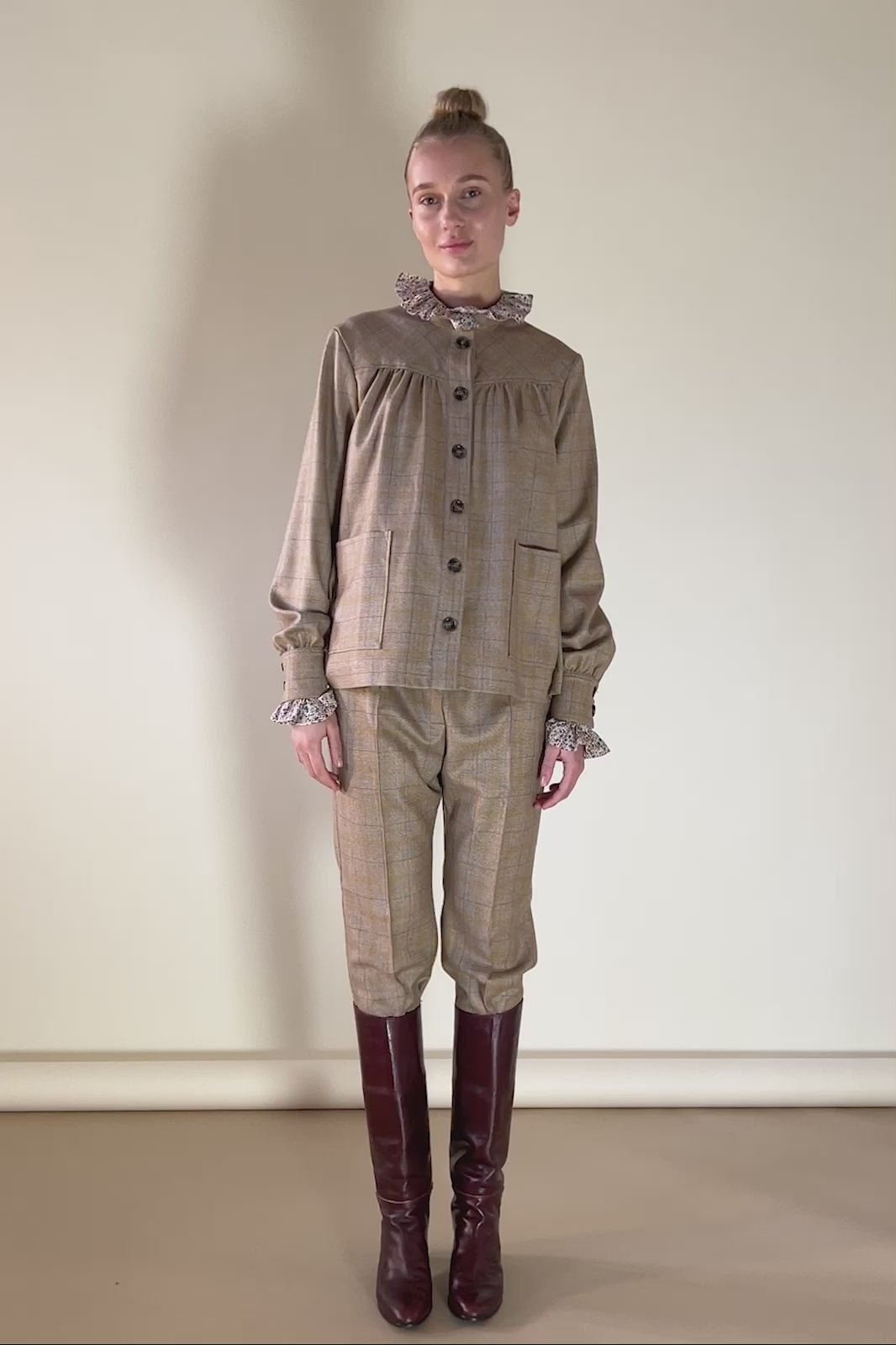 Woman in beige check print wool pants and jacket with buttons and pockets and shirt with frills
