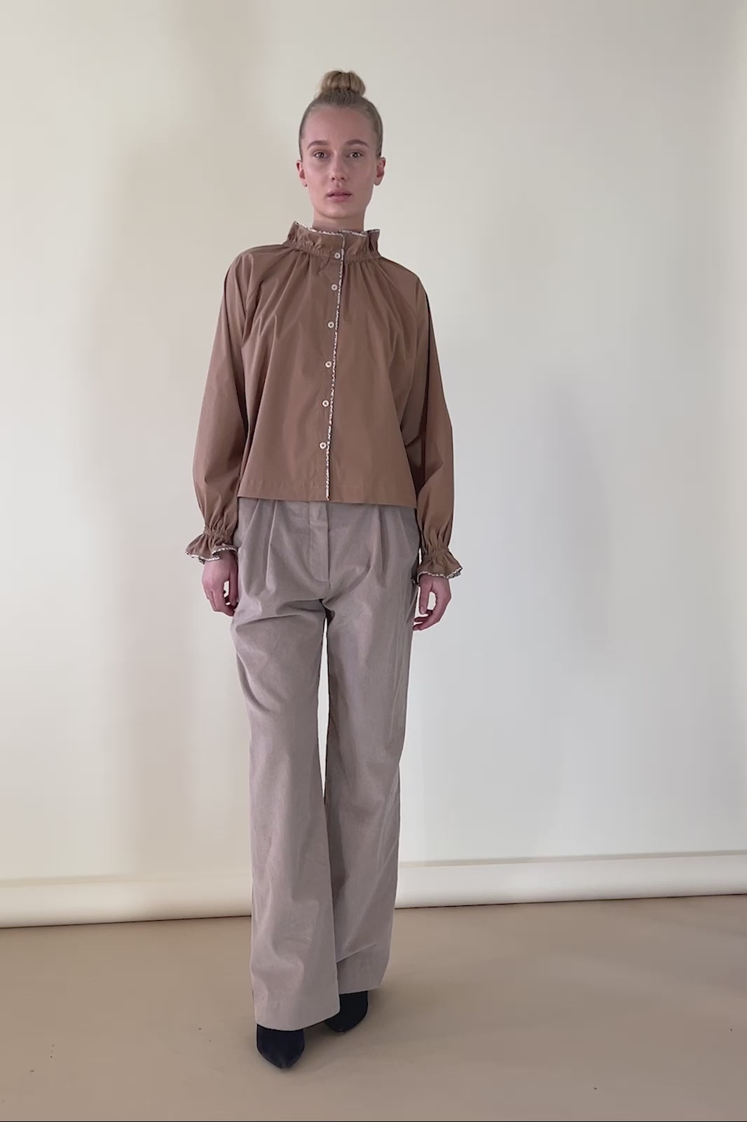 Women in wide baby corduroy pants and toffie brown shirt with buttons and frills
