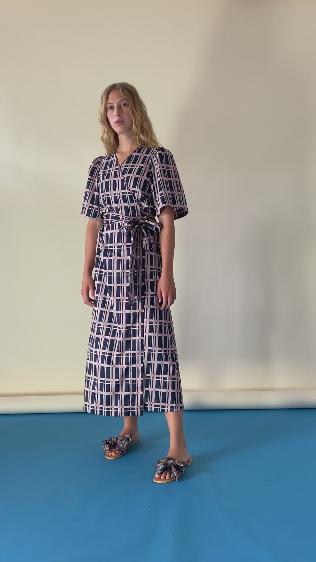 Woman in black and pink checked wrap dress in Liberty cotton with short sleeves and sandals with bows