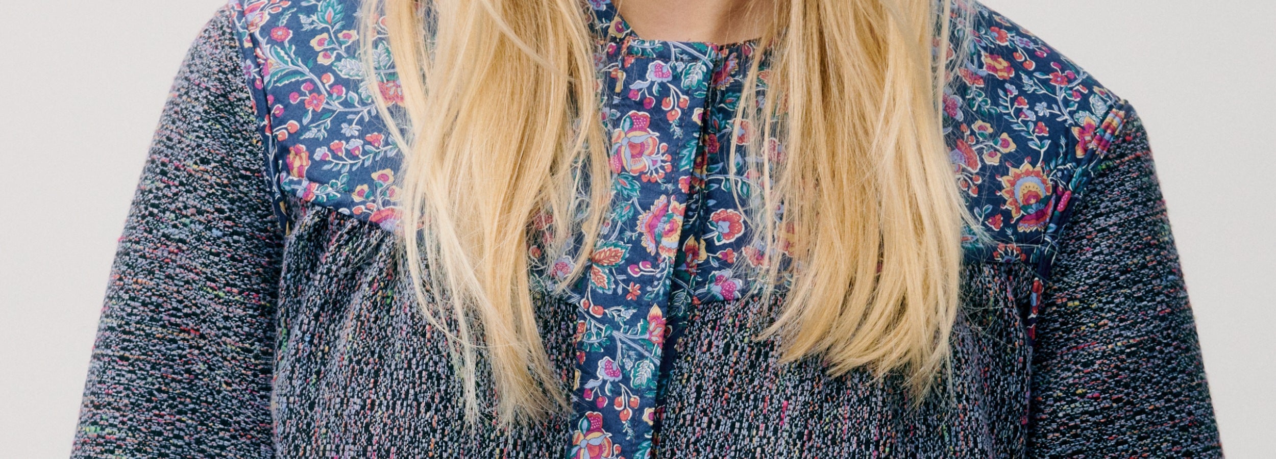 Woman wearing a blue floral jacket with a plain background