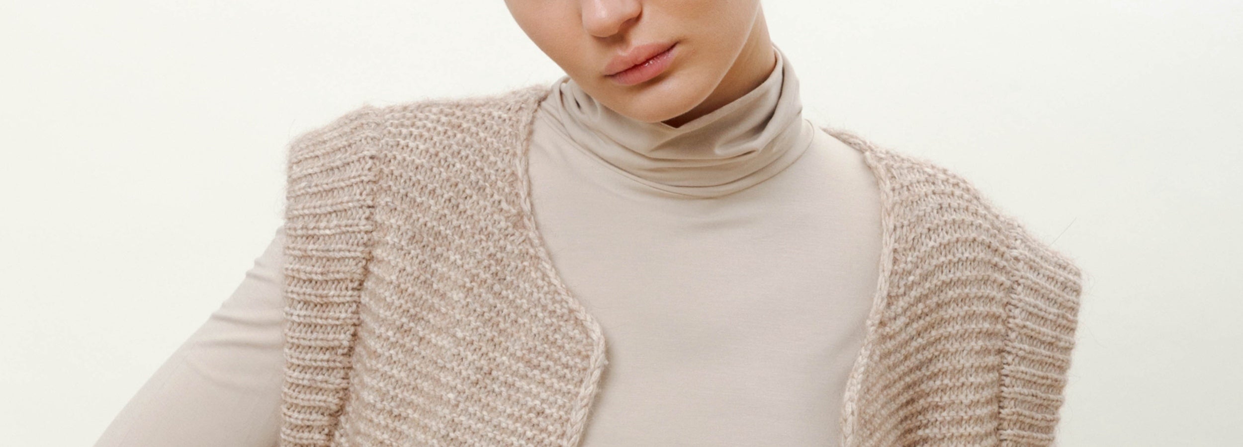 Woman in cream colored roll neck and knitted wool vest