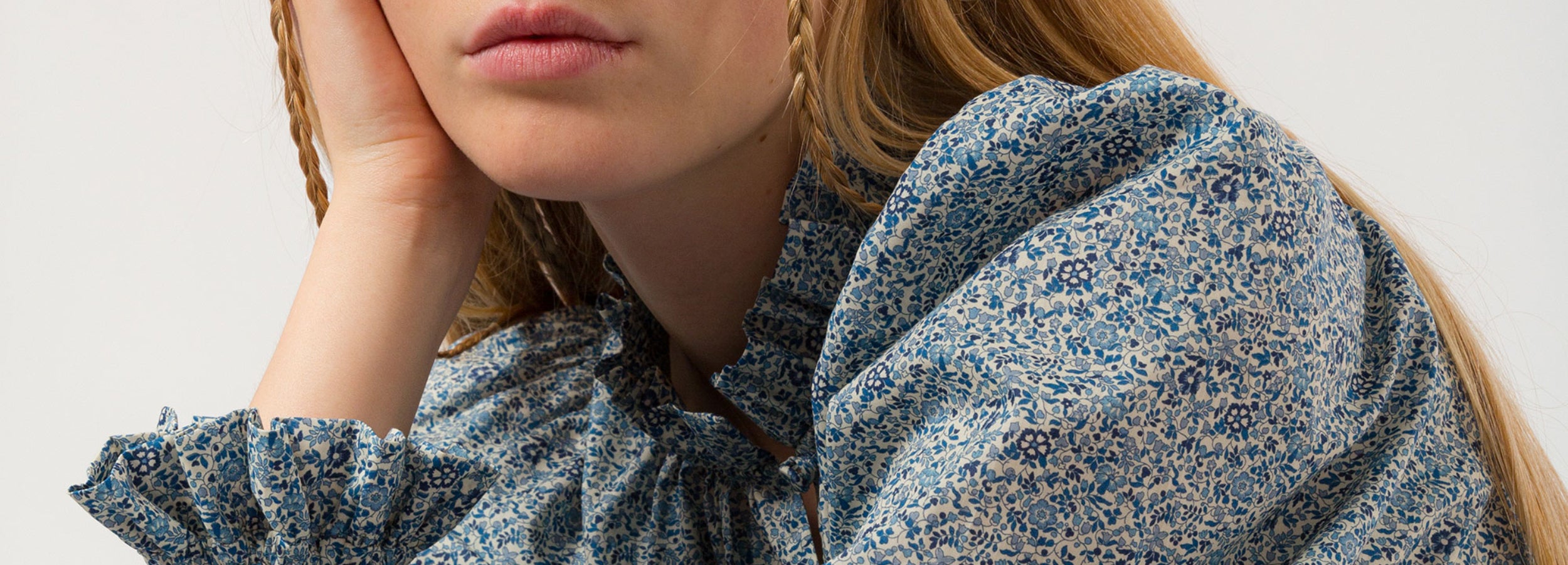 Woman with long hair dressed in long sleeved blouse with frills in small blue print cotton Liberty fabric