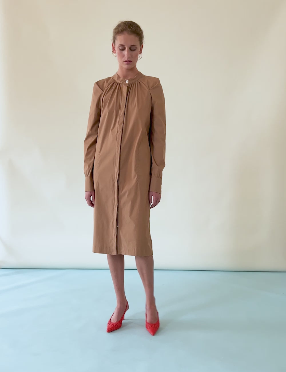 Woman in brown shirt dress with long sleeves and red shoes