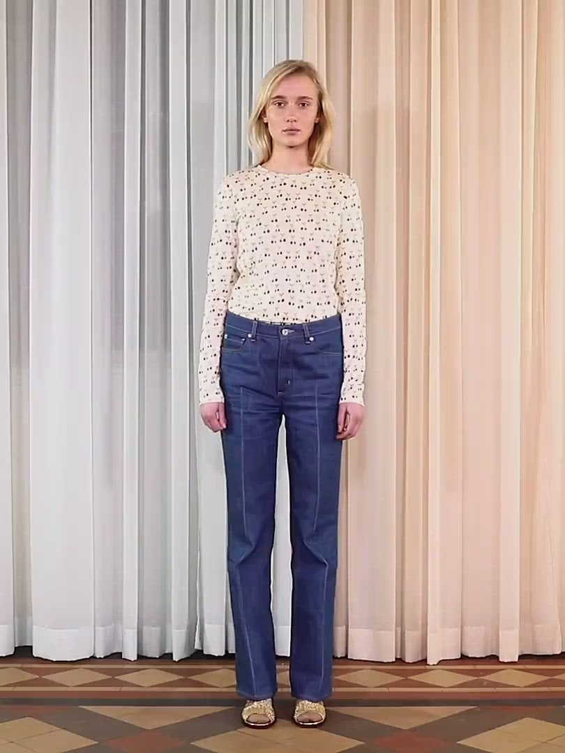 Woman in long sleeve white t-shirt with cherry pattern and blue trousers