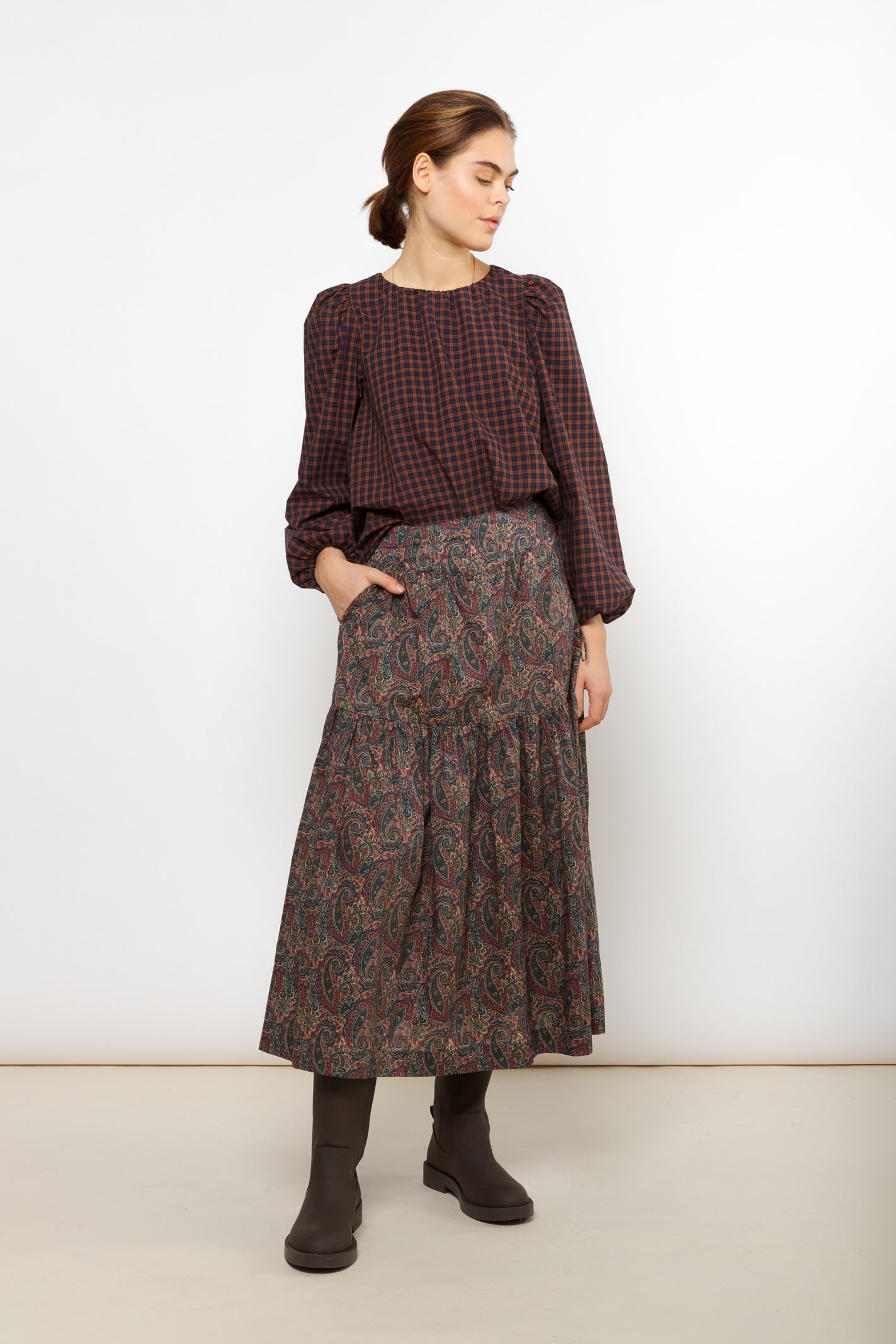 Woman in long multi colored skirt with paisley pattern and checked blouse