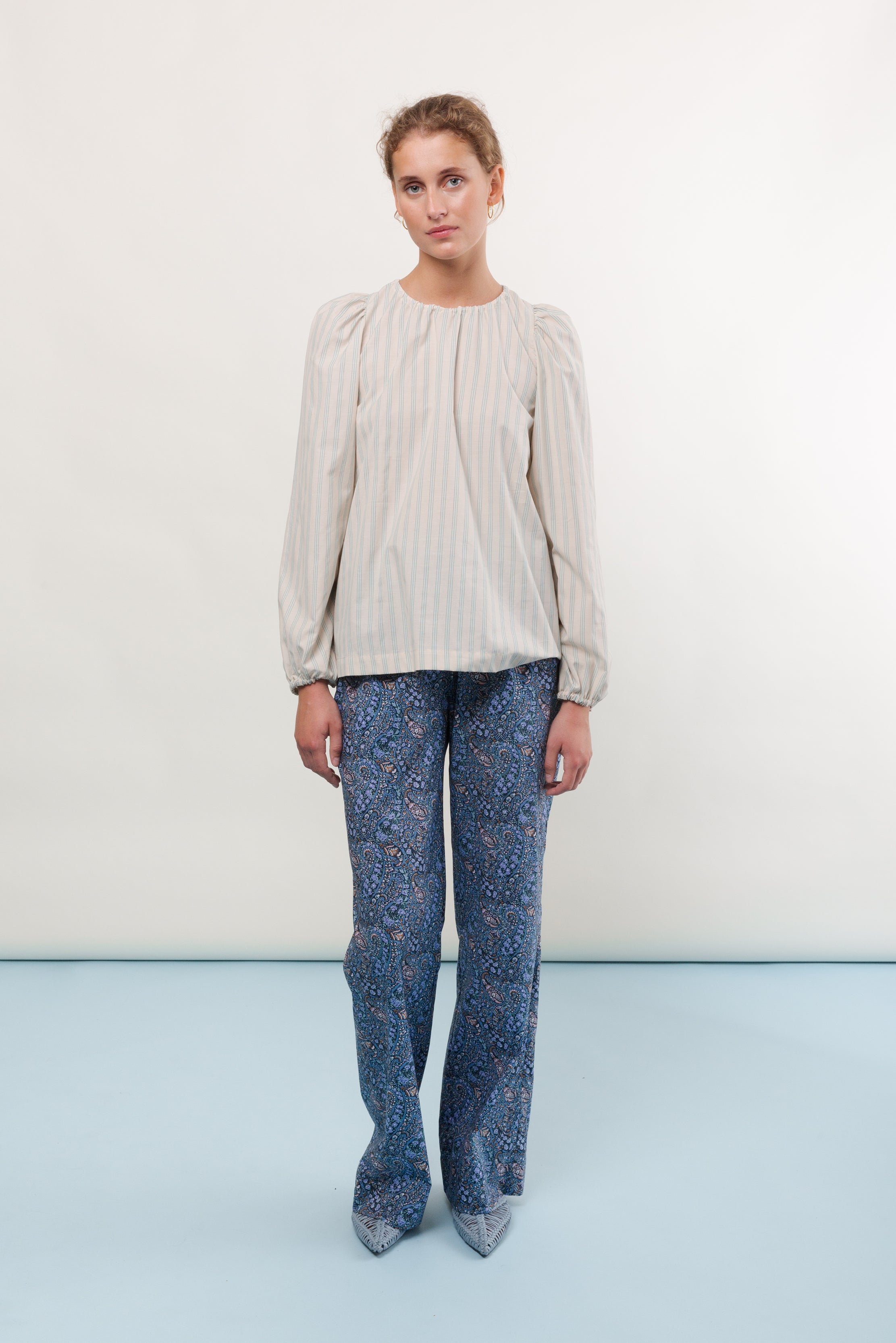 Woman in striped blouse with long sleeves and blue pants