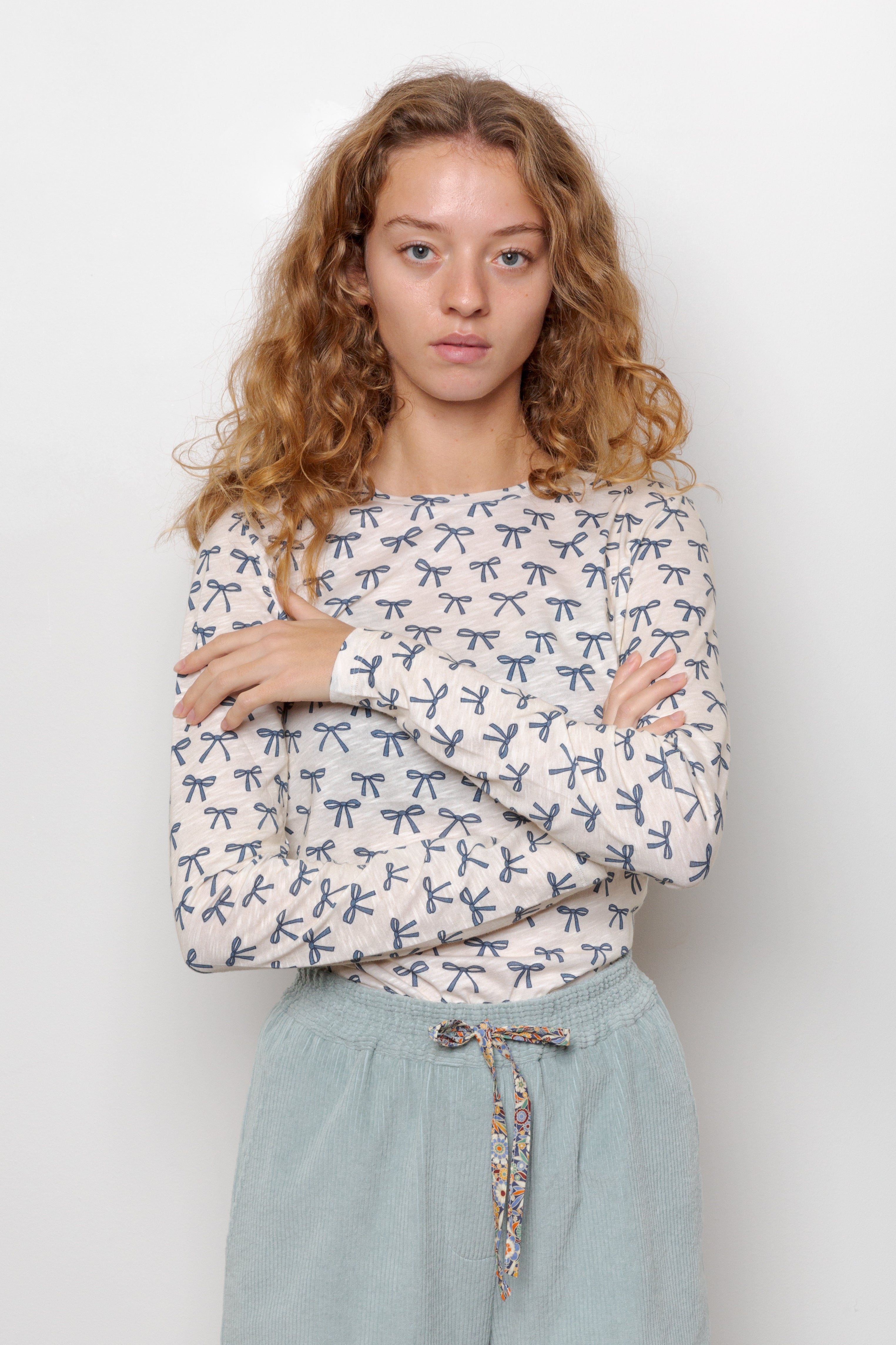 Woman in long sleeve white t-shirt with blue bows pattern and blue pants