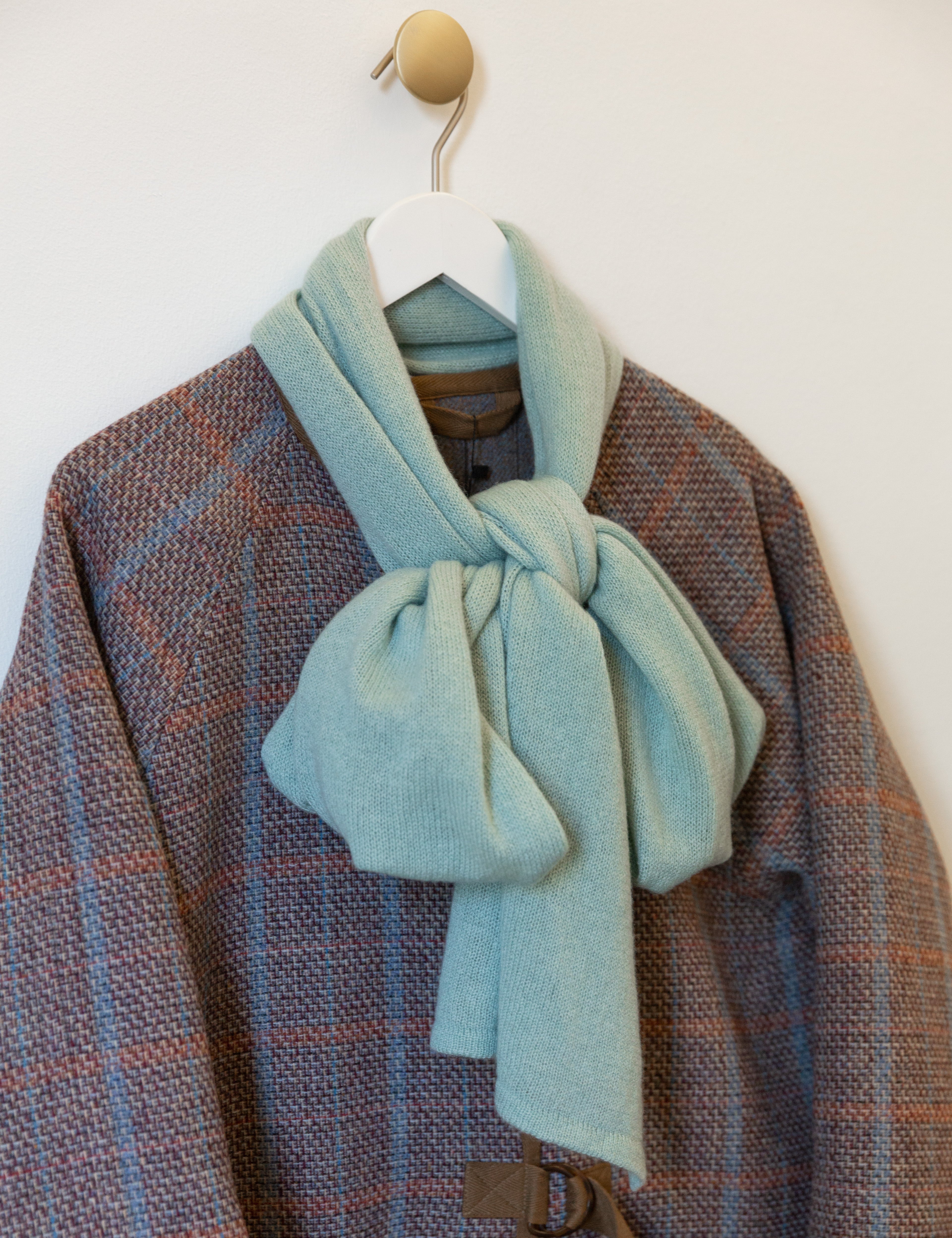 Mint green cashmere scarf tied to a bow on multi colored jacket