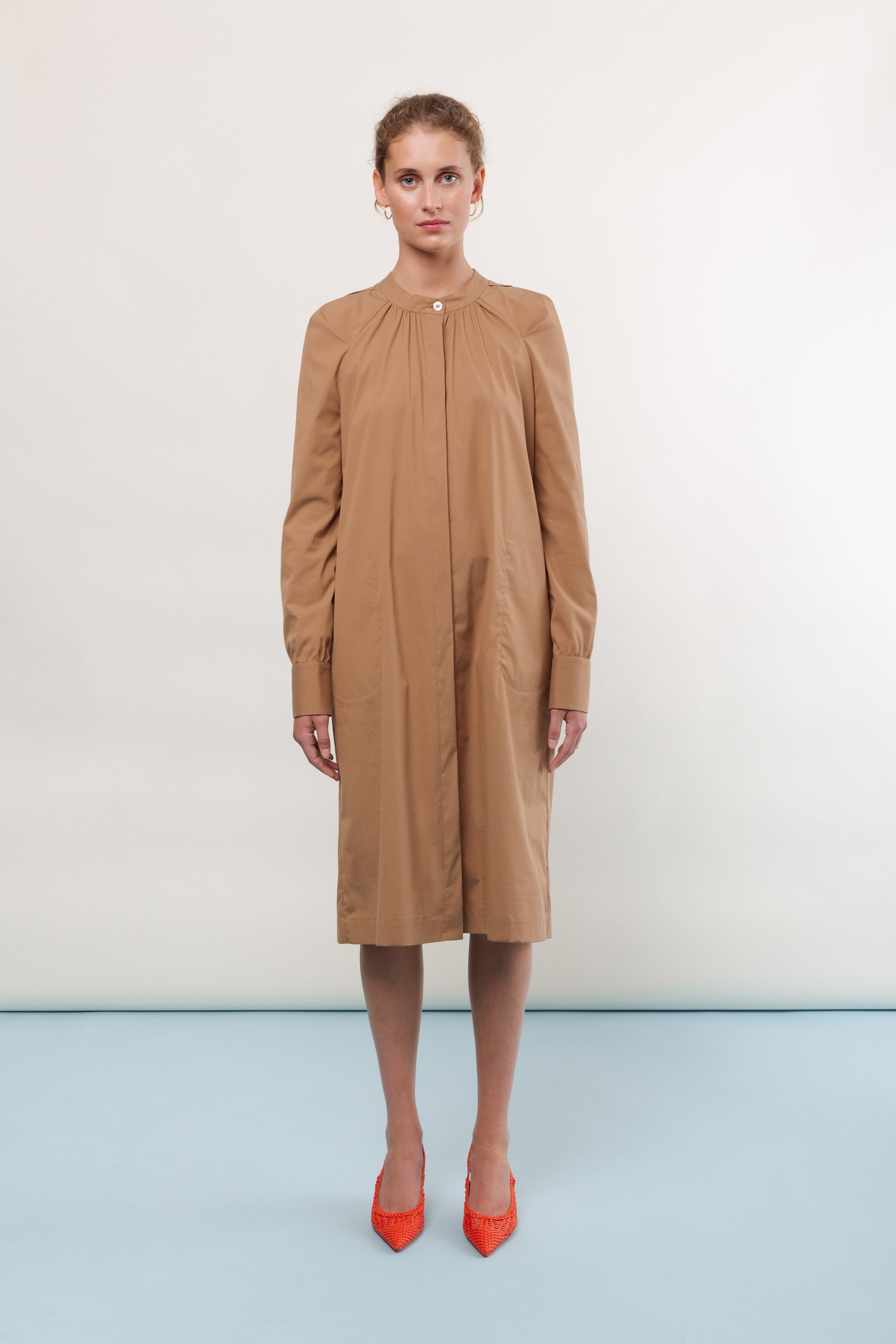 Woman in brown shirt dress with long sleeves and red shoes