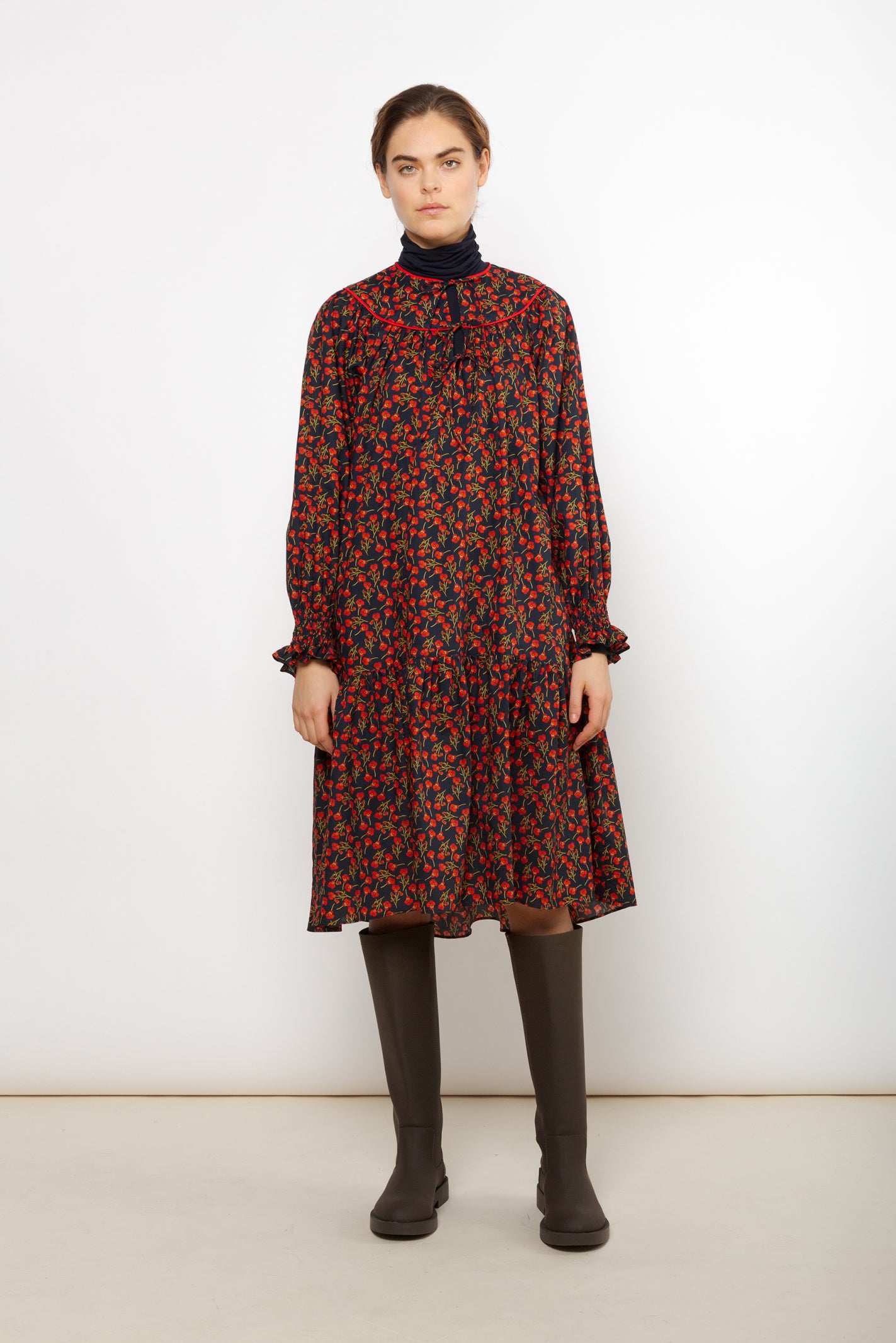Woman in short Liberty cotton dress with red rose pattern and puffed sleeves with detailed cuffs