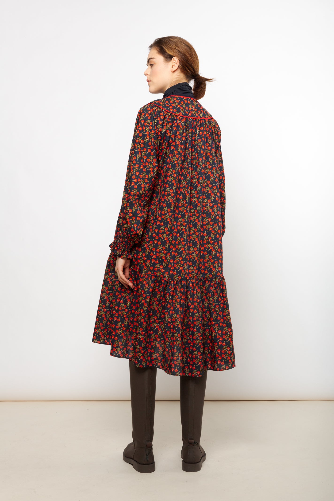 Woman in short Liberty cotton dress with red rose pattern and puffed sleeves with detailed cuffs