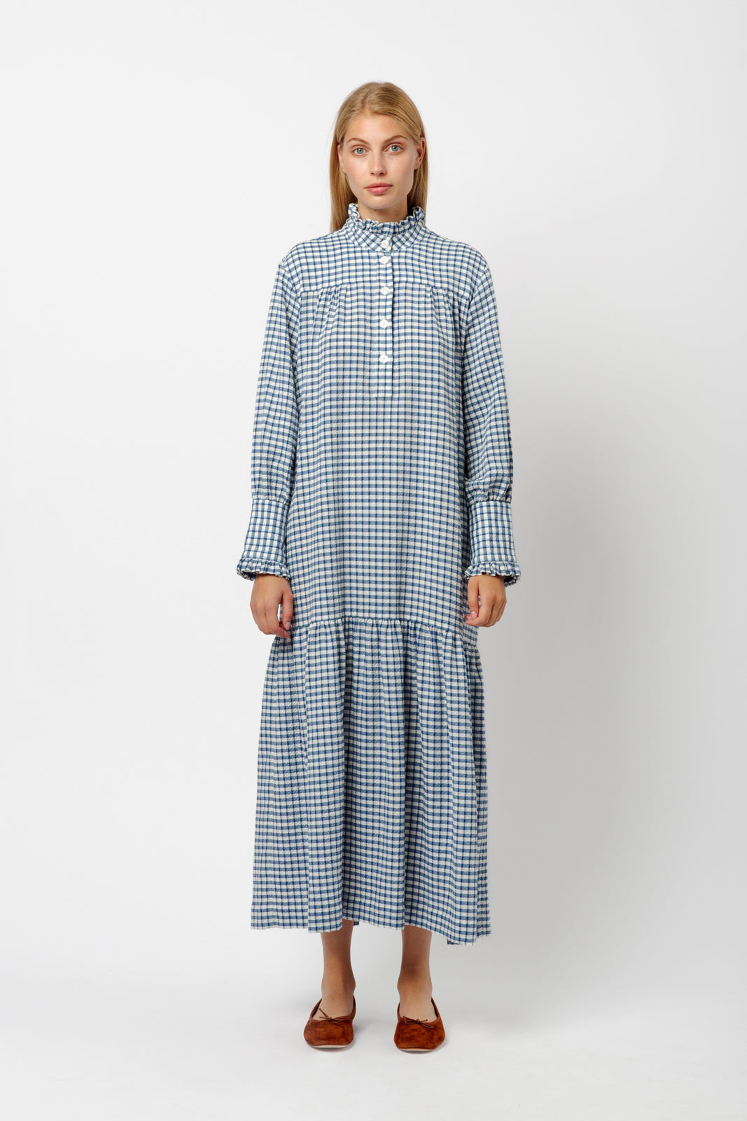 Woman in blue and white checked cotton dress with long sleeves, buttons, cuffs and collar with ruffles