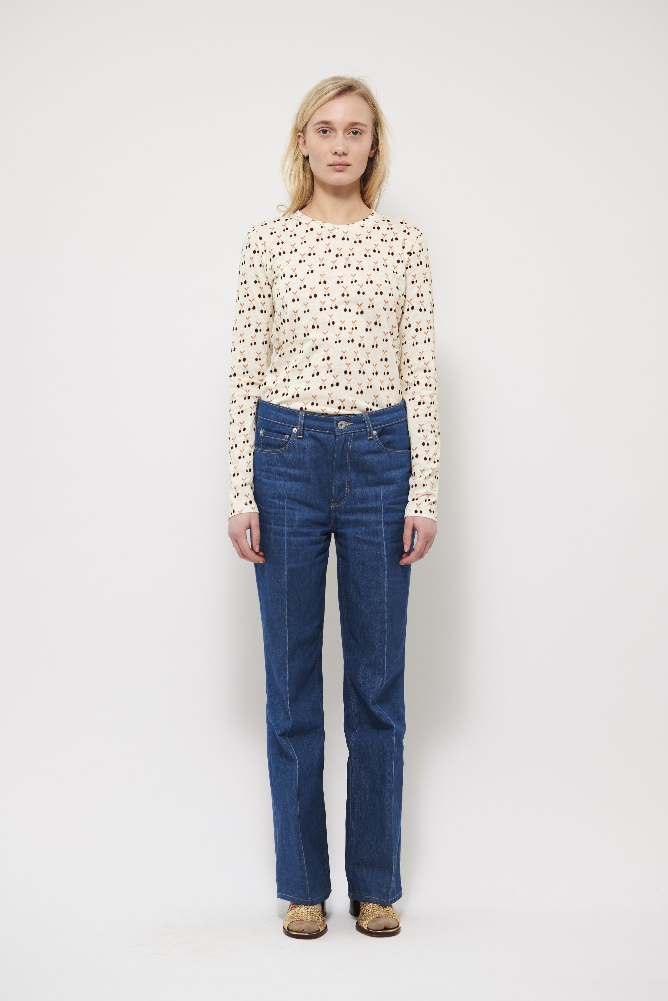 Woman in long sleeve white t-shirt with cherry pattern and blue trousers