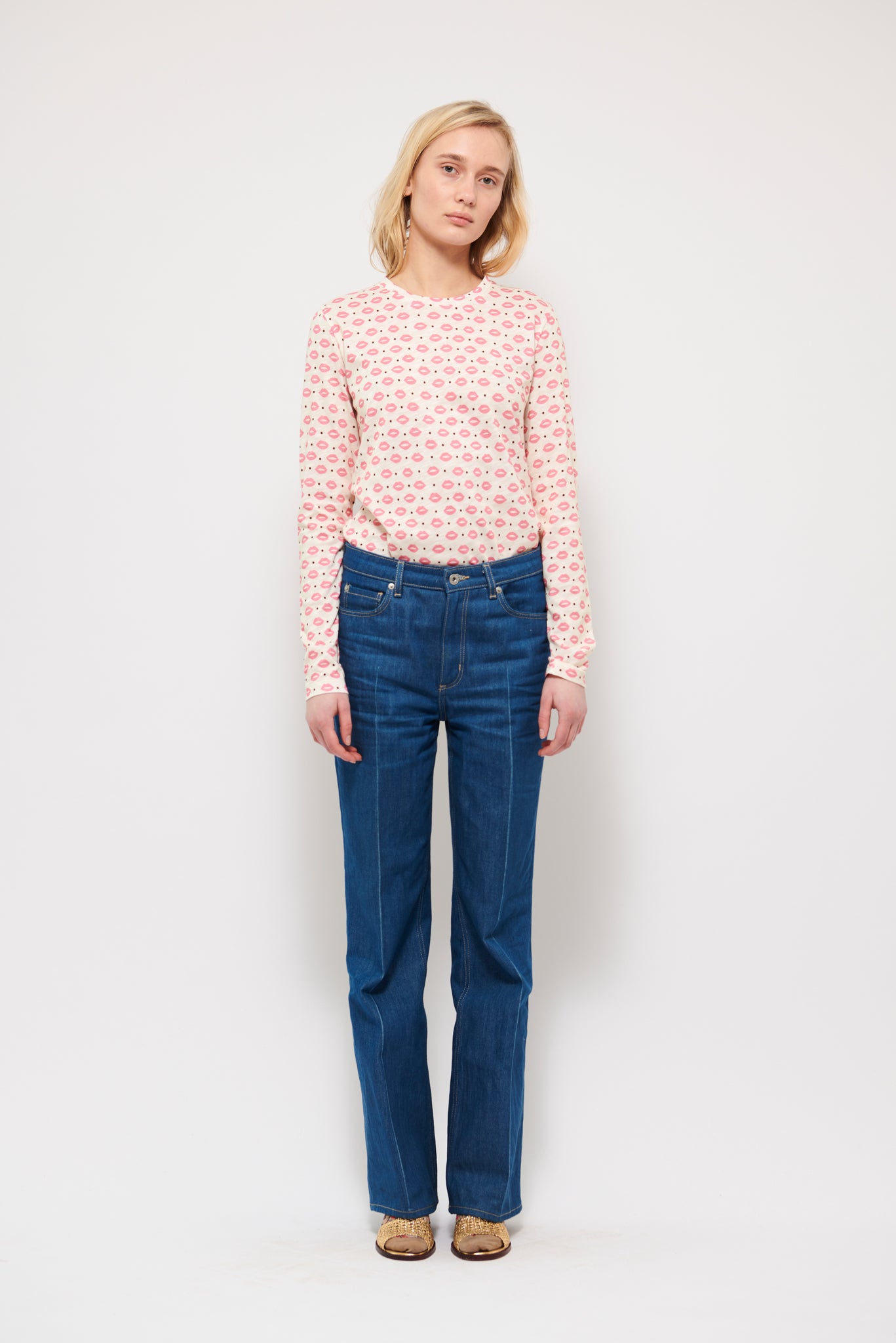 Woman in long sleeve white t-shirt with pink lips pattern and blue trousers