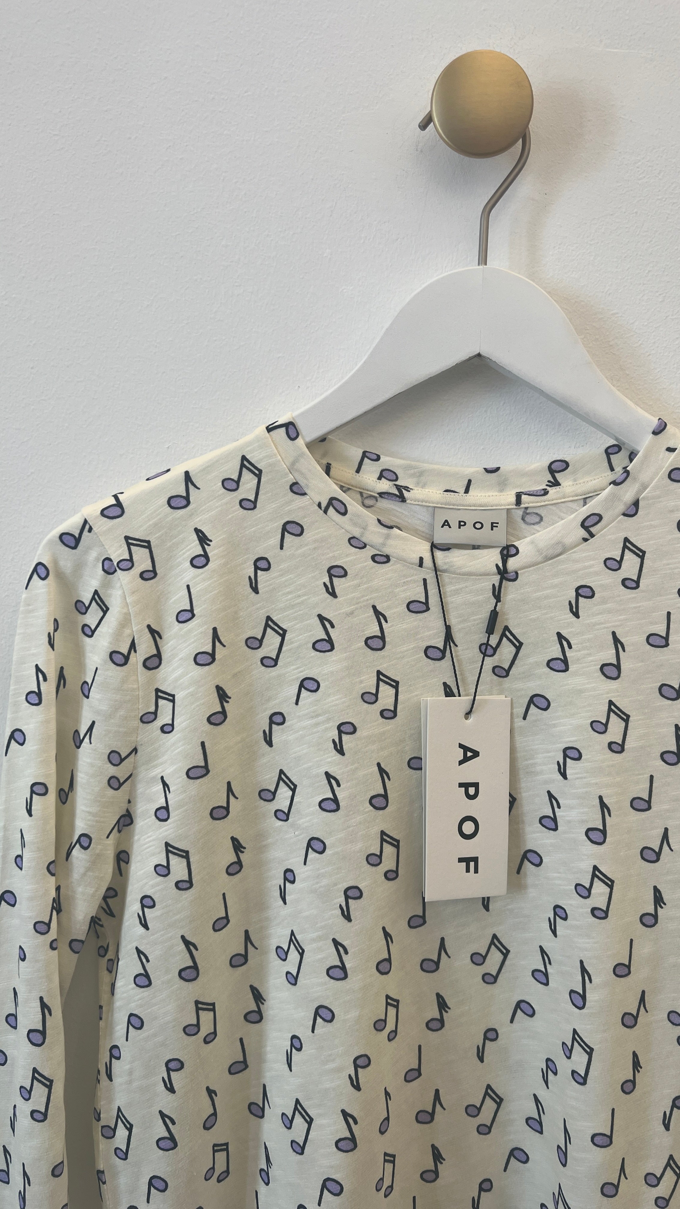 Women's long sleeve white t-shirt with blue notes pattern on hanger with Apof tag