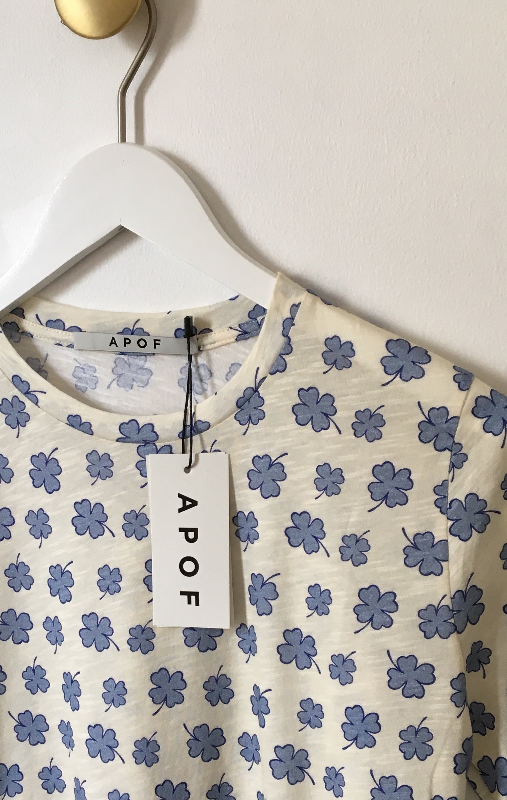 Women's long sleeve white t-shirt with blue four-leaved clovers pattern on hanger