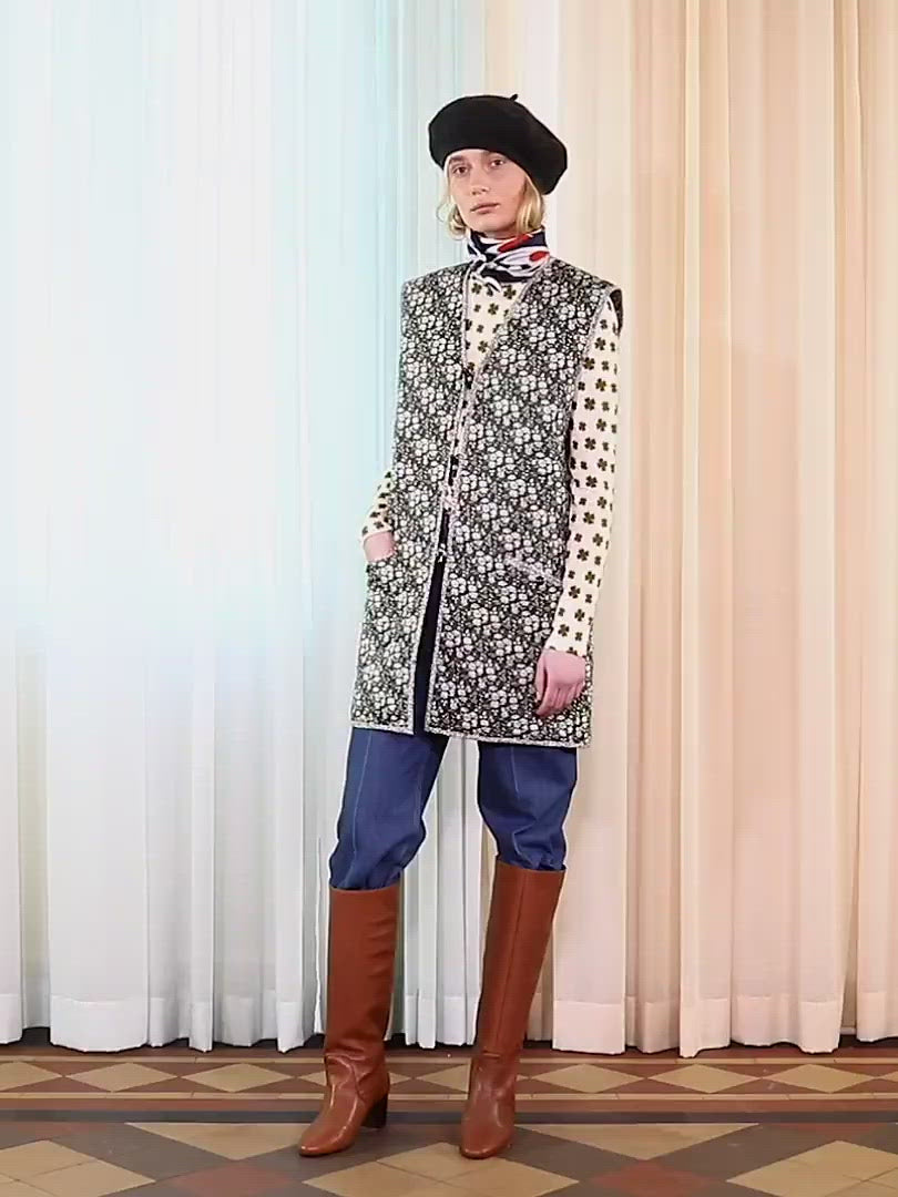 Woman in long sleeve white t-shirt with green four-leaved clovers pattern and green flower vest