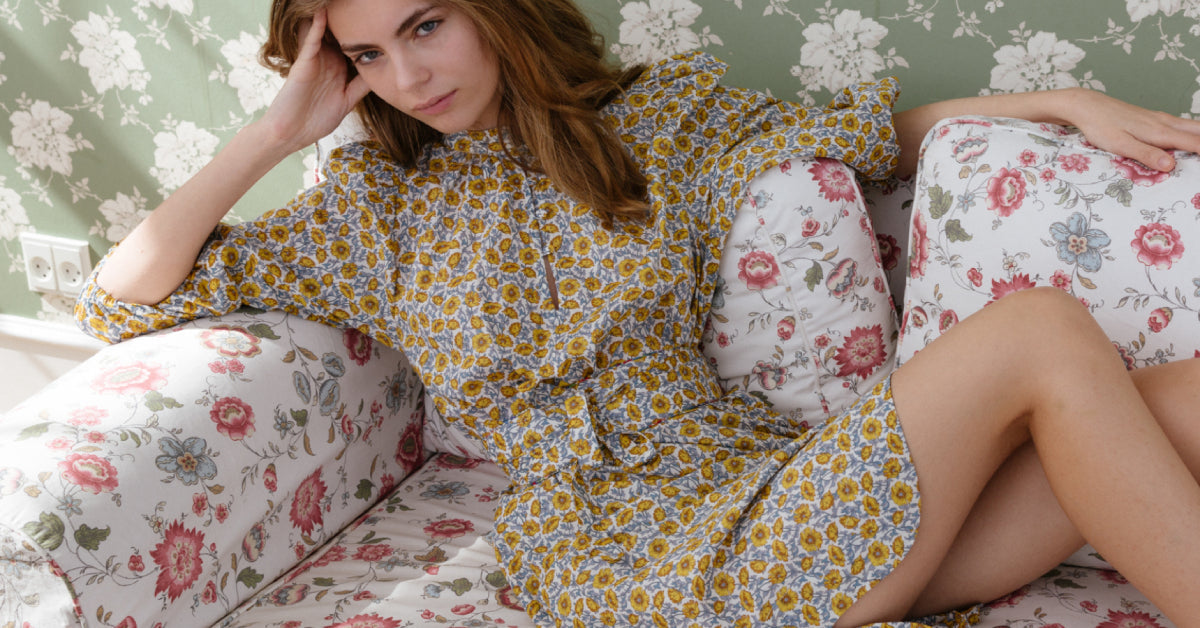 Woman in yellow floral patterned Liberty cotton dress with long puff sleeves and matching belt