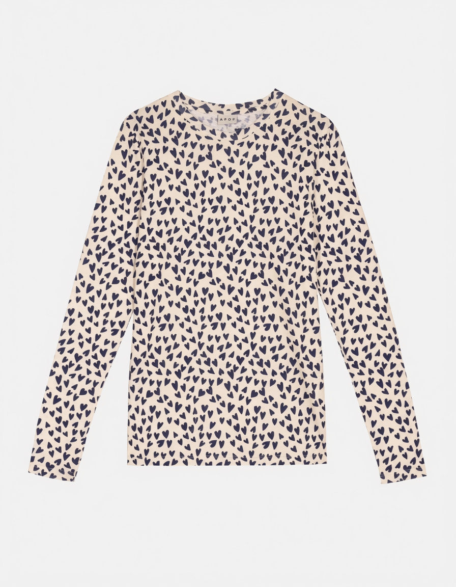 Ein langärmliges Damen-T-Shirt mit Rundhalsausschnitt, das ein durchgehendes kleines Herzmuster in Dunkelblau auf warmem Cremehintergrund zeigt, flach auf einem hellgrauen Hintergrund liegend.