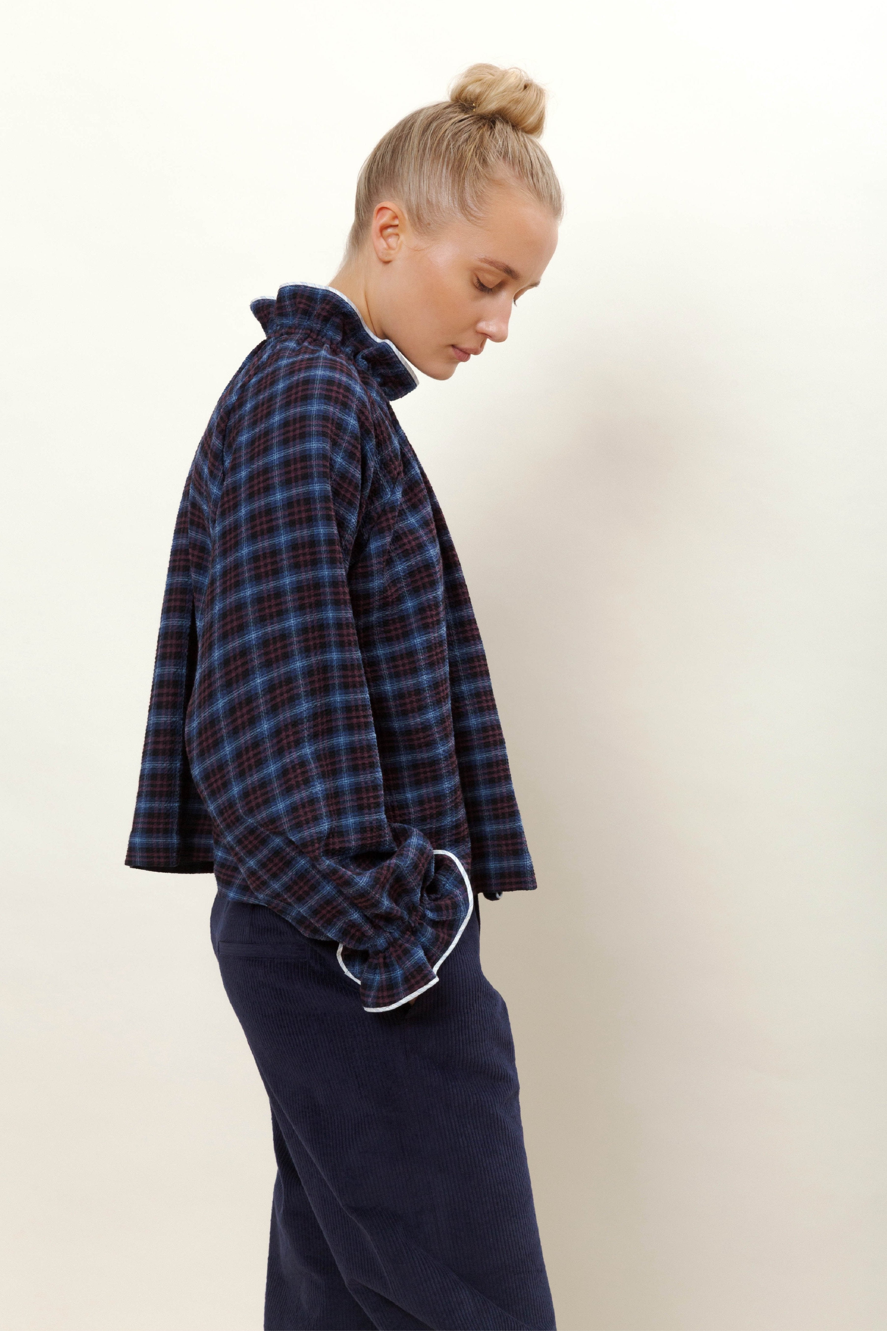 Woman in blue pants and long sleeved blouse with blue and red check pattern