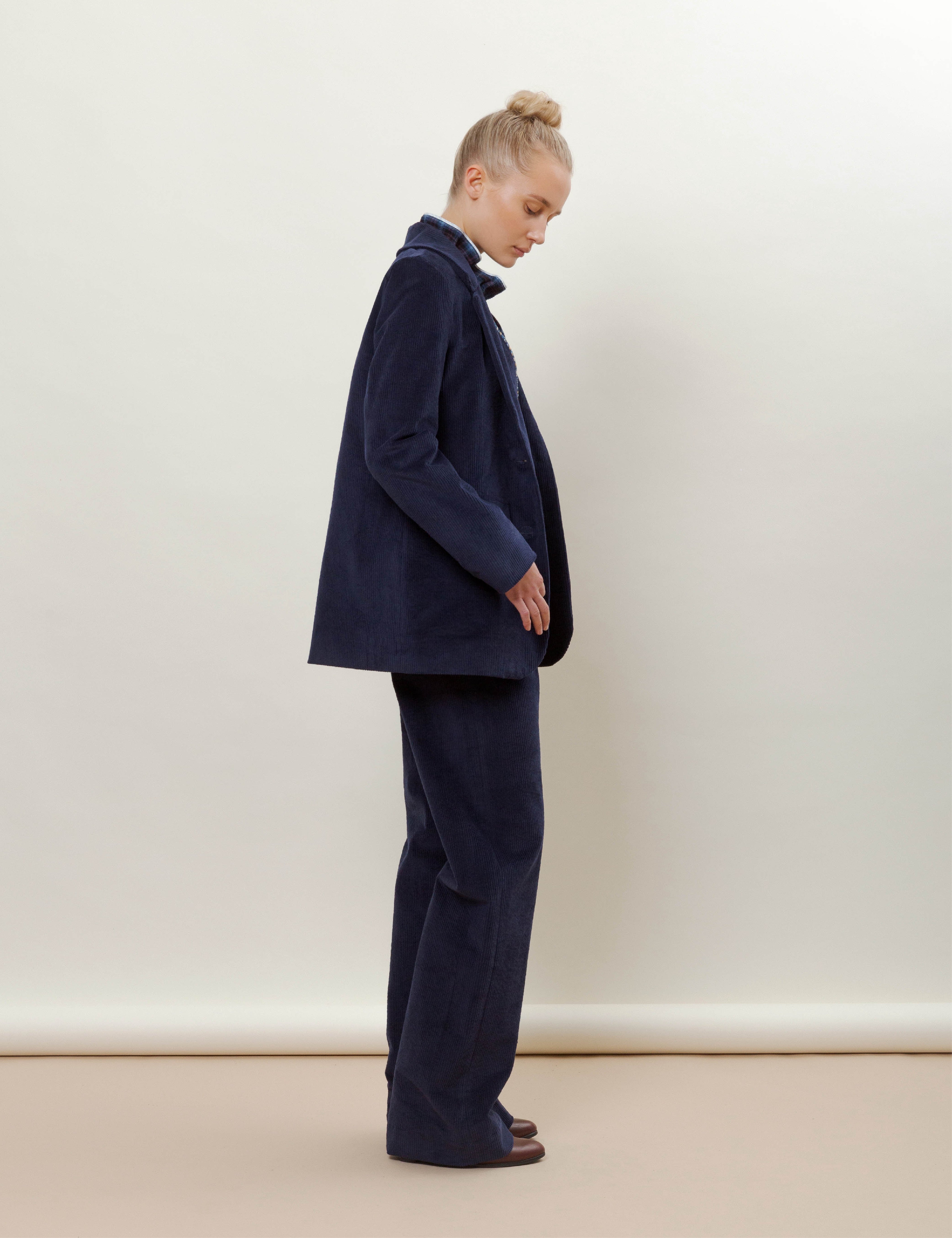 Woman in blue corduroy jacket and wide pants and blue checked blouse with ruffles