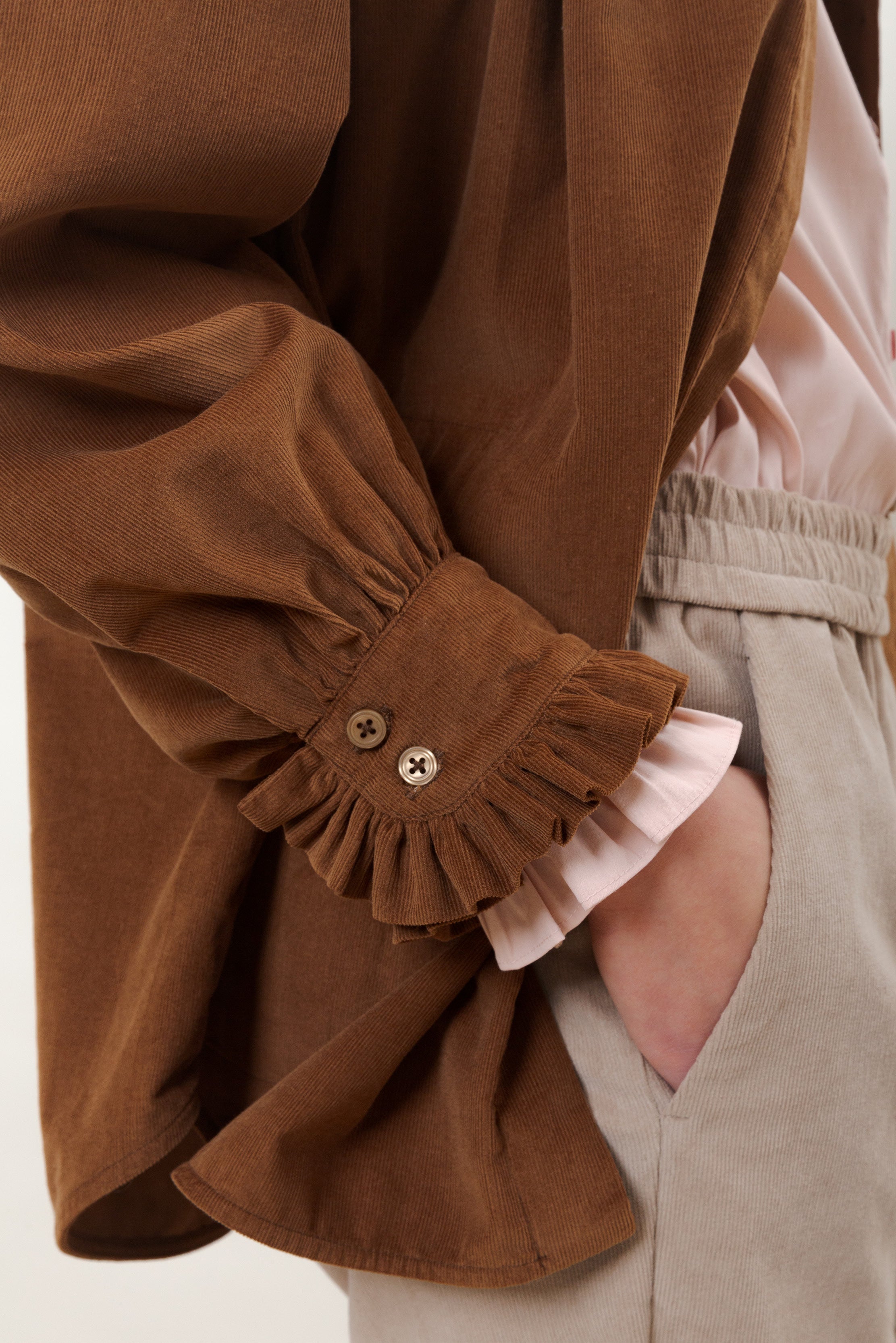 Woman with brown corduroy blouse with frilled cufs and beige corduroy pants