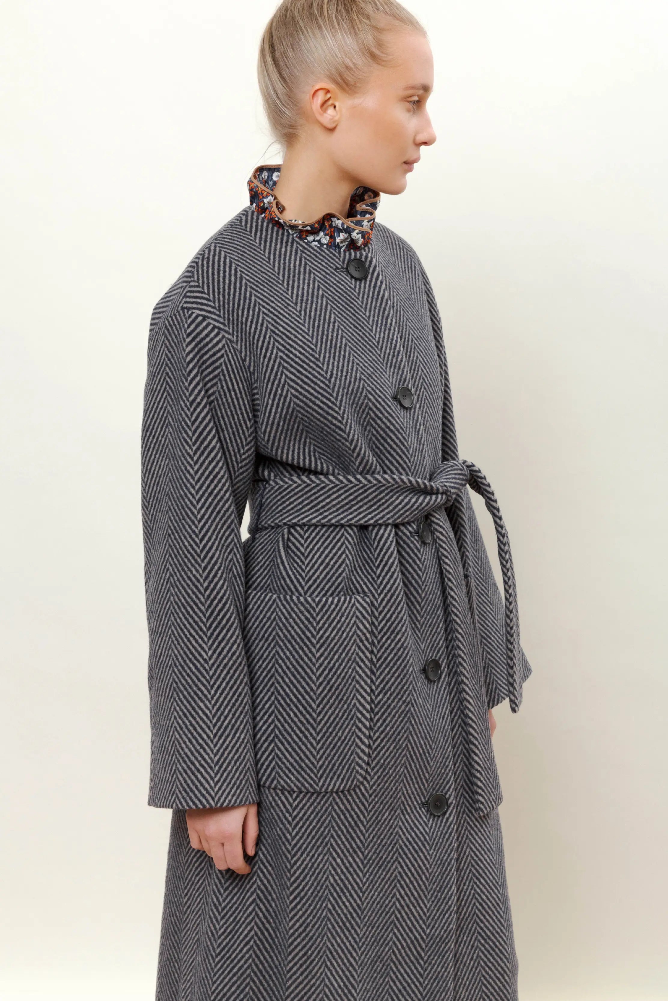 Woman in blue herringbone coat with belt and buttons