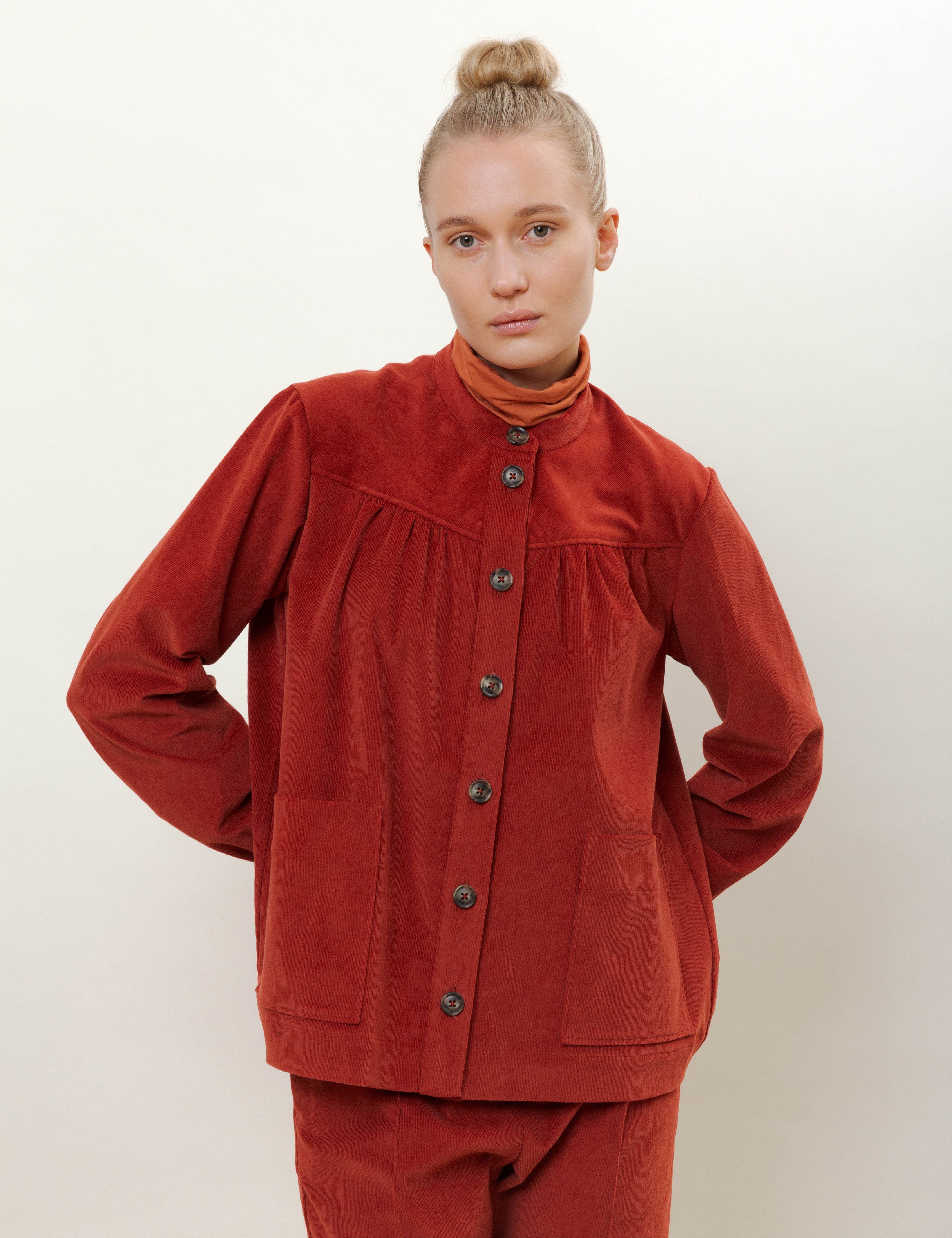 Woman in red corduroy pants and jacket with pockets and buttons