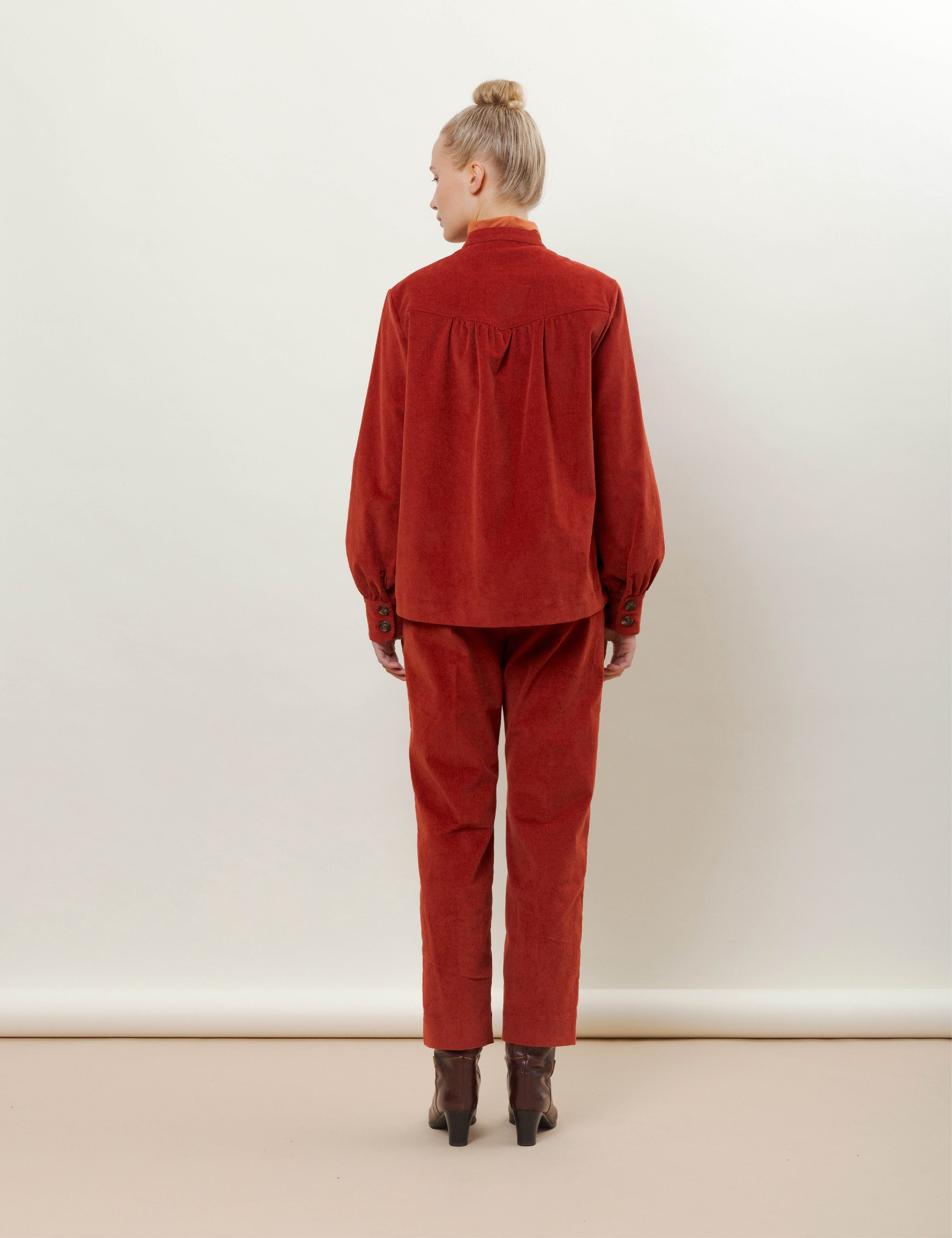 Woman in red corduroy pants and jacket with pockets and buttons