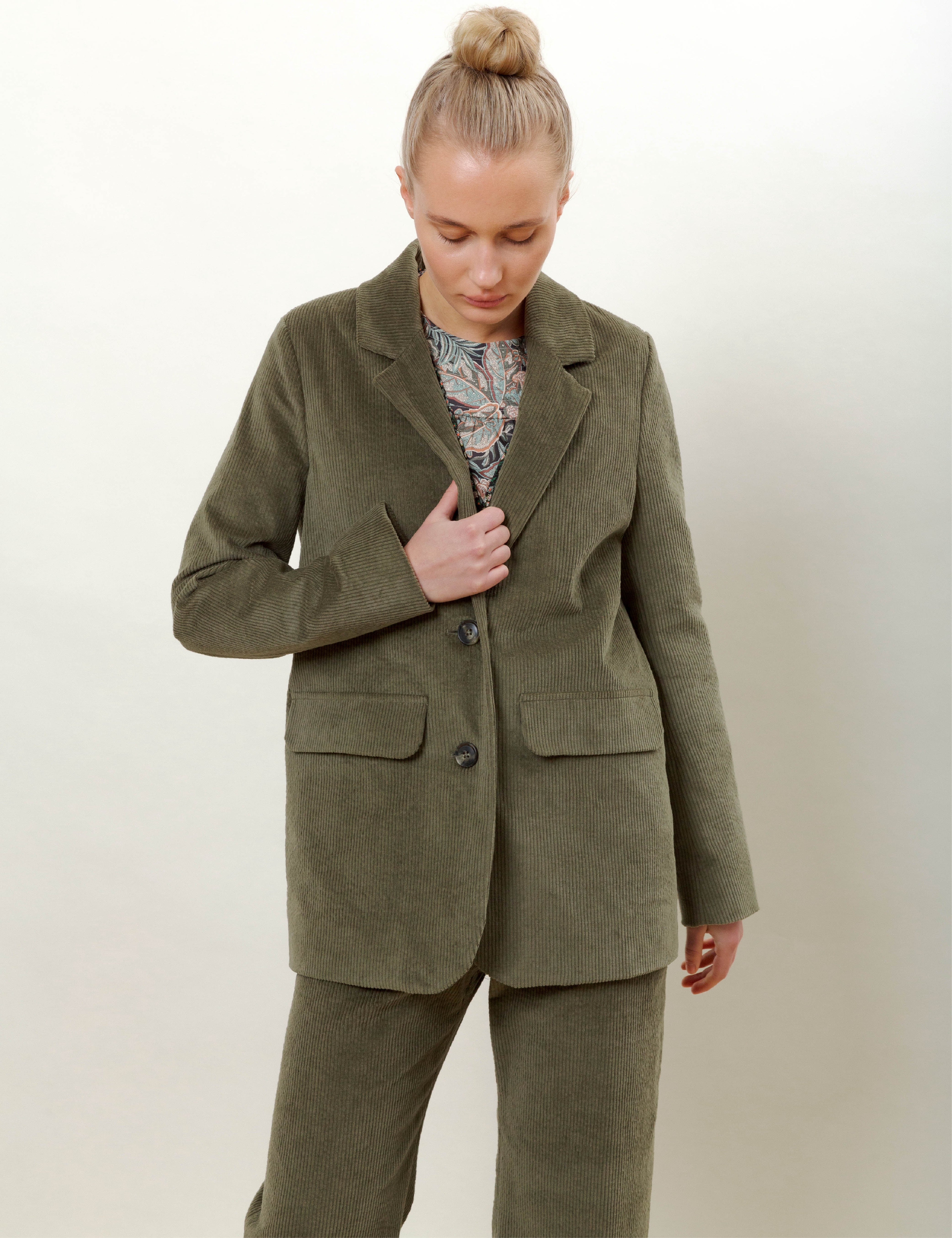 Woman in olive green corduroy jacket and pants and flower patterned top