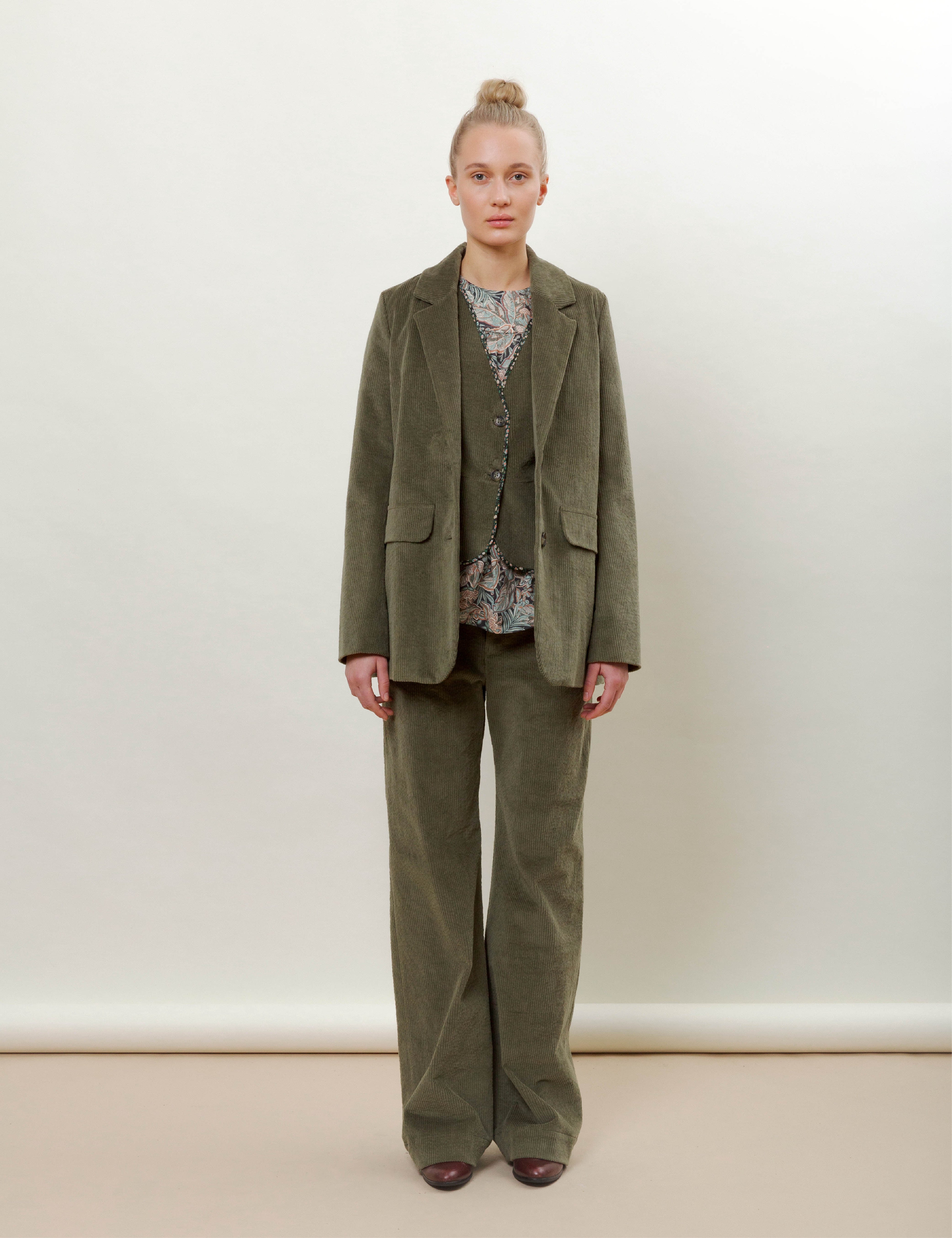 Woman in olive green corduroy jacket, pants, vest and flower patterned top