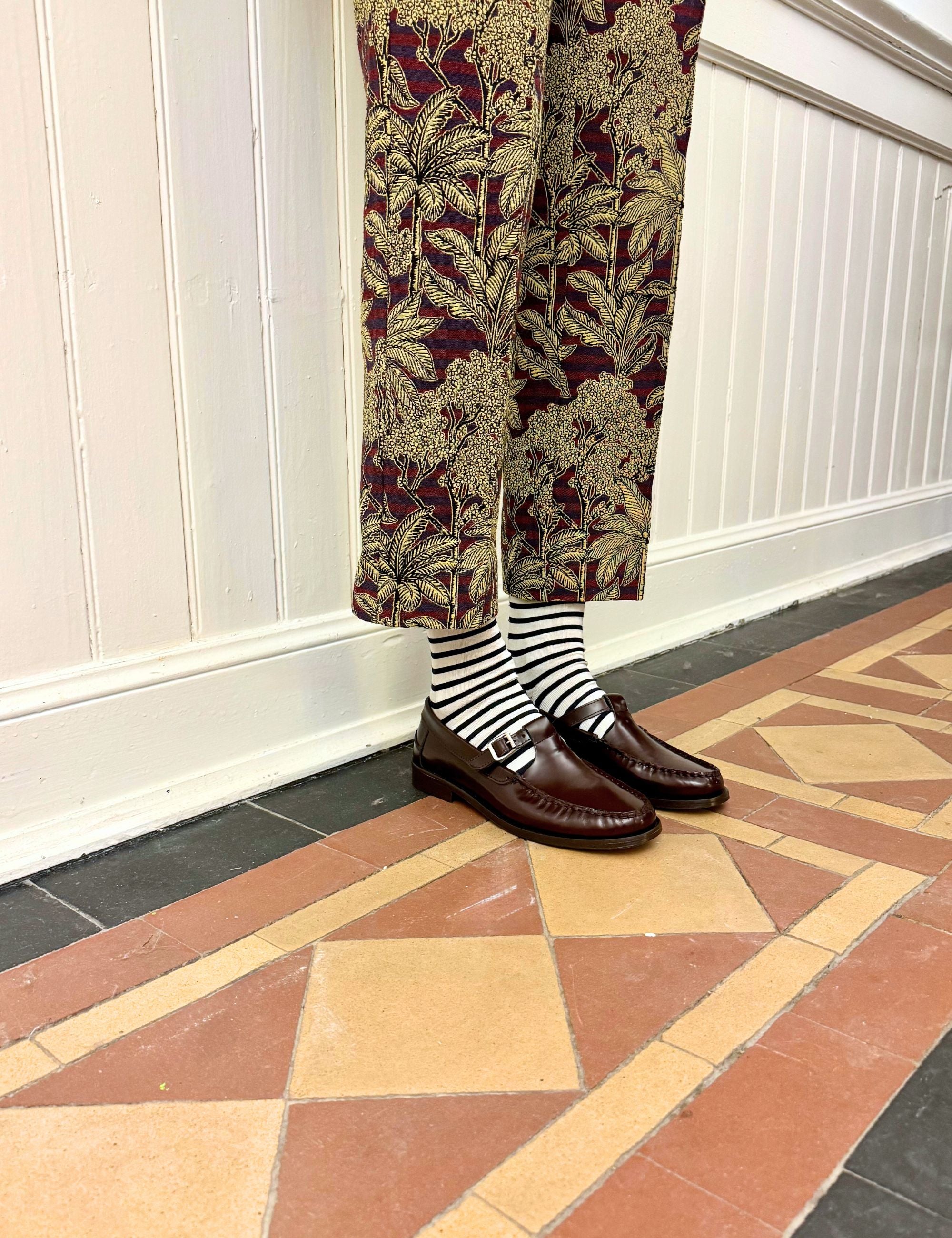 Woman in palm print pants striped socks and burgundy colored mocasins