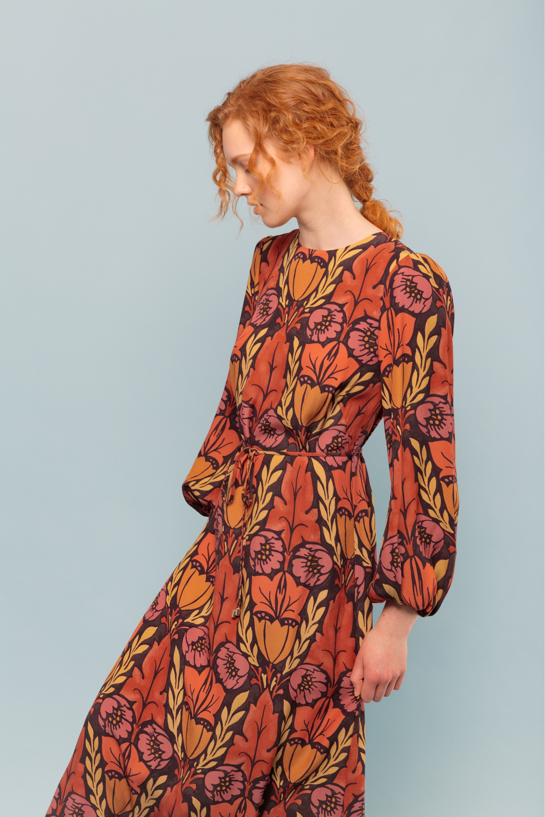 Woman in maxi dress in viscose twill with pink, yellow and orange flower pattern and puffed sleeves