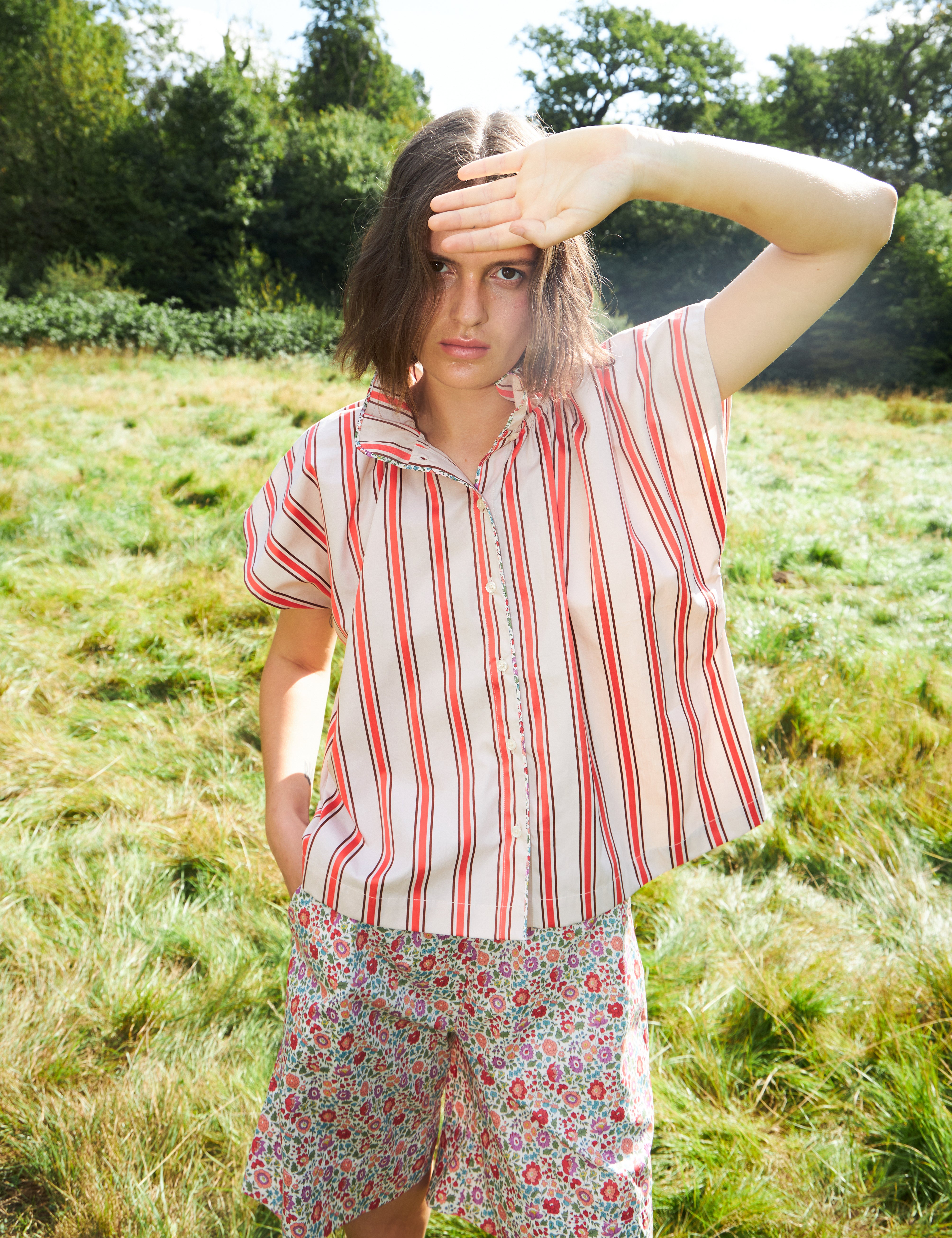 Woman in red and white striped sleeveless top with stand collar and shorts with multi-colored small flower pattern