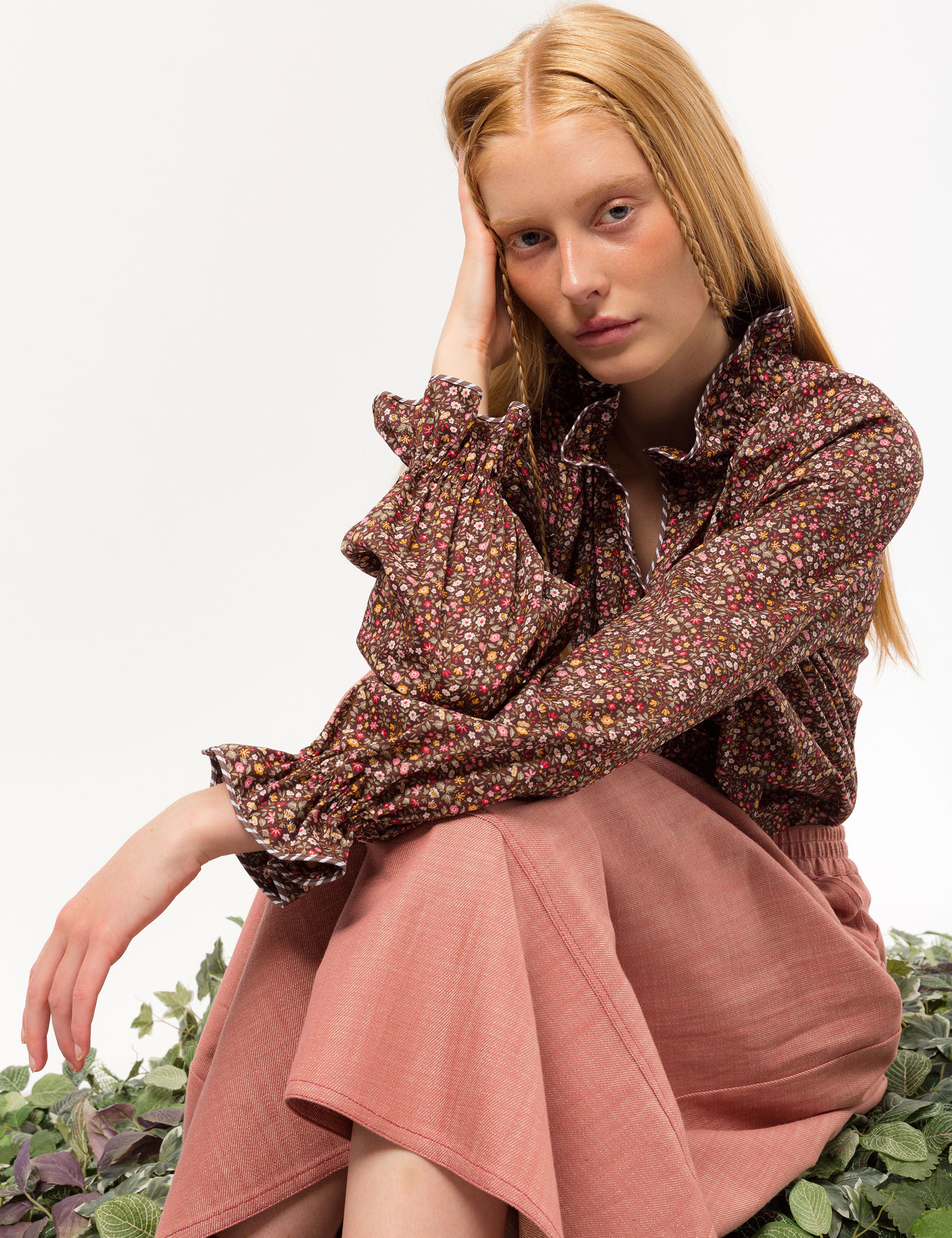 Woman in liberty cotton brown floral print shirt with frilled cuffs and collar and pink cotton skirt