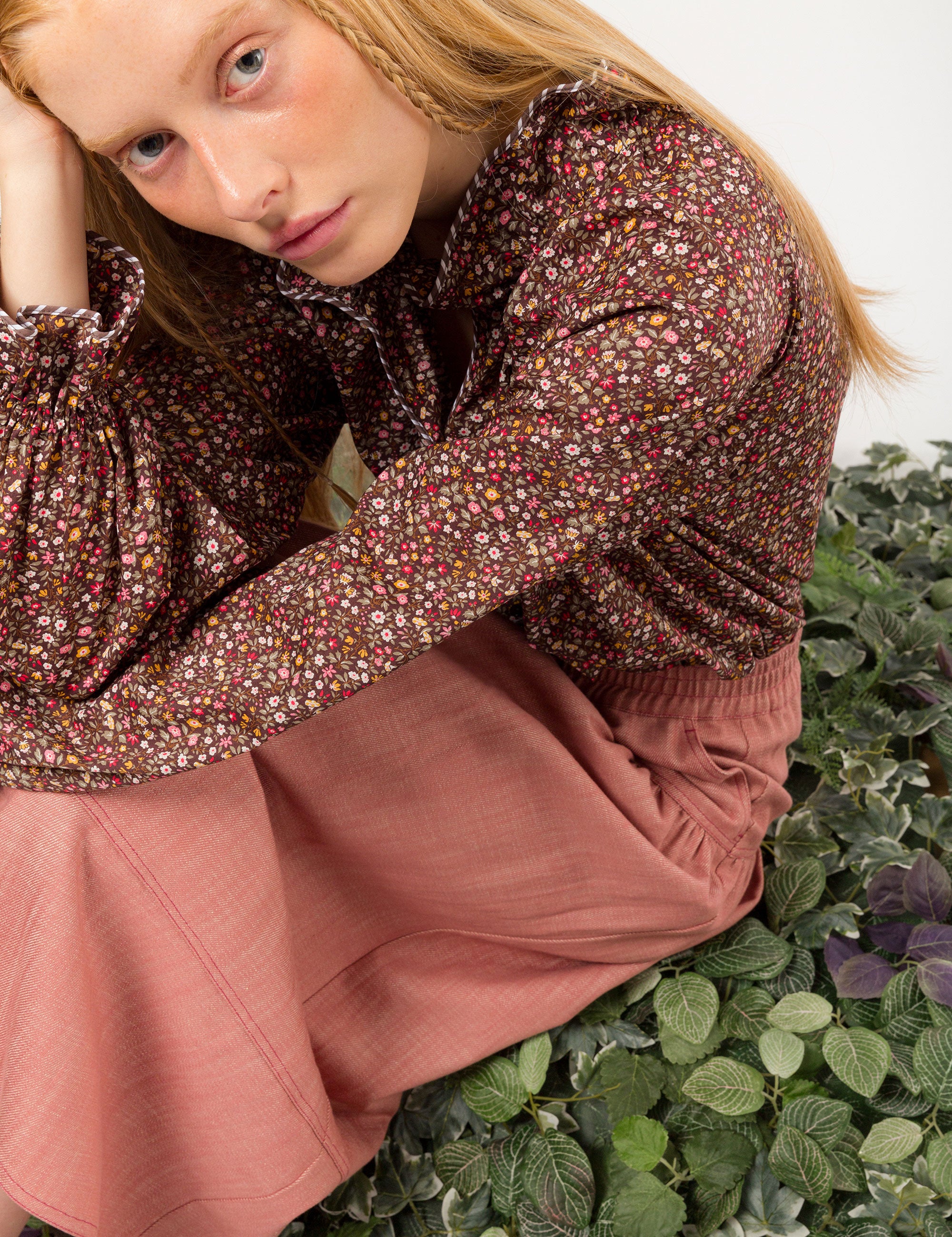 Woman in liberty cotton brown floral print shirt with frilled cuffs and collar and pink cotton skirt